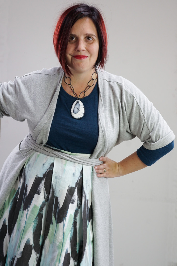 one dress challenge, creative capsule outfit inspiration: wrap dress as a duster over a patterned skirt and teal sweater with a bold gemstone necklace