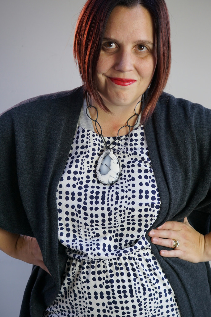 one dress challenge, creative outfit layering: oversized cardigan and patterned dress over wrap dress with chunky gemstone statement necklace