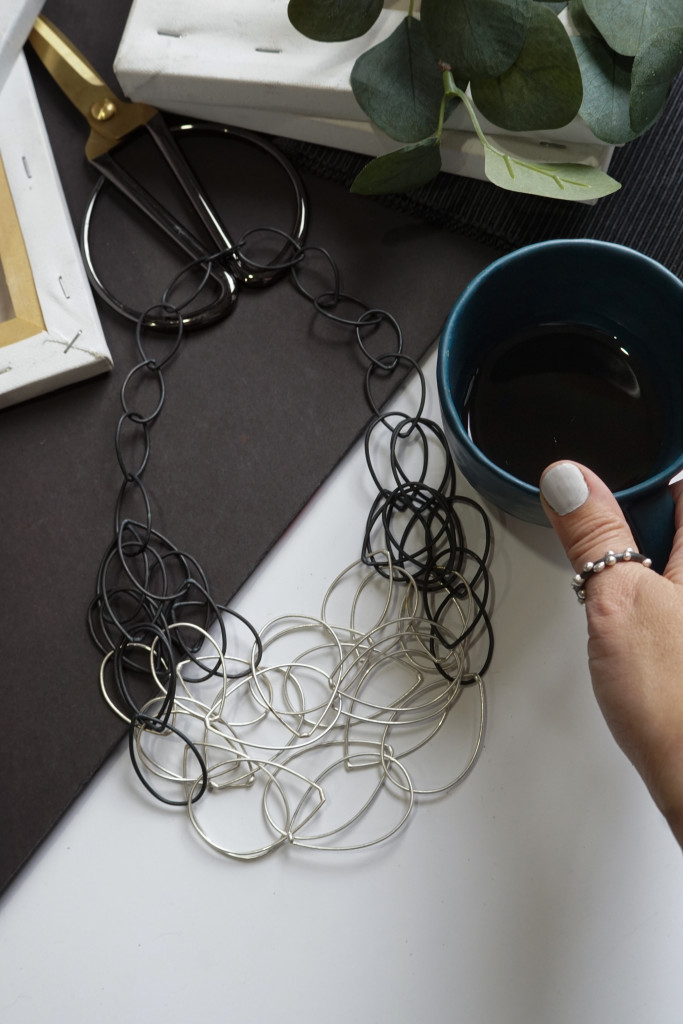 artist maker morning flatlay: handmade ceramic tea cup, mixed metal chain link statement necklace, handmade silver on steel thumb ring