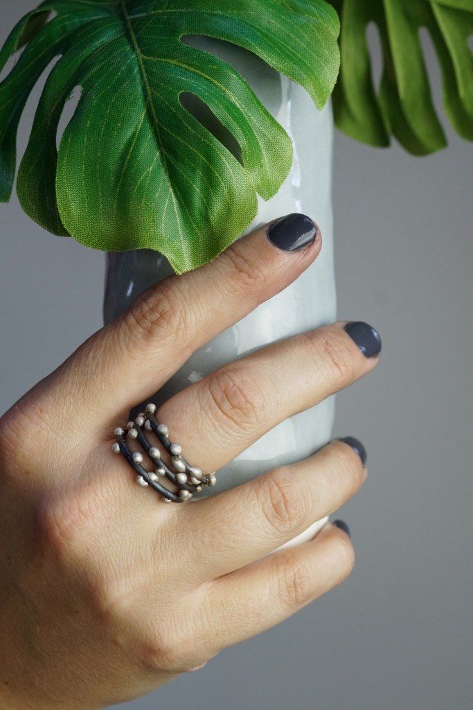 faux monsterra plant,  handmade ceramic vase, and mixed metal stacking rings