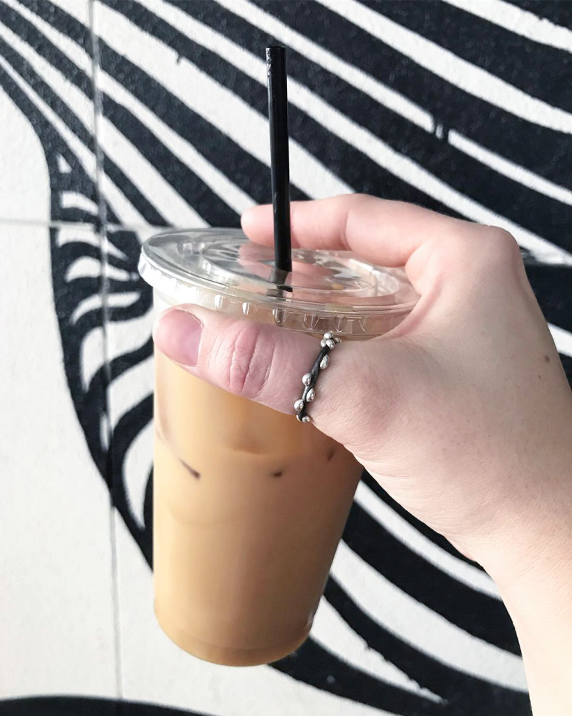 iced latte, mixed metal thumb ring, and black and white painted wall in Sarasota, Florida