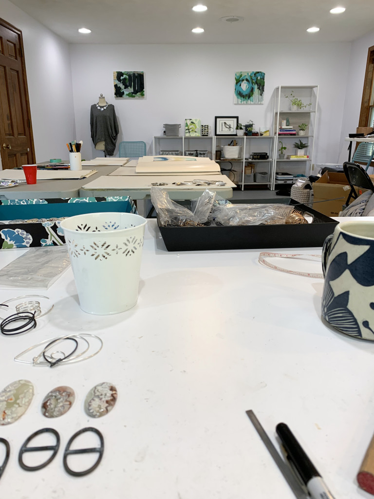 view of the metalsmithing bench and jewelry studio of megan auman with abstract art displayed on the back wall