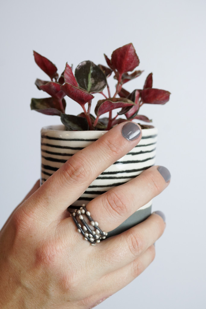 handmade mixed metal stacking rings, striped ceramic cup, and peperomia plant