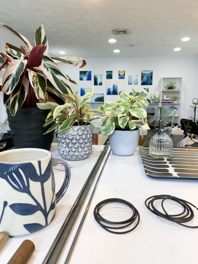 work table of metalsmith megan auman with plants and paintings in the backgroun