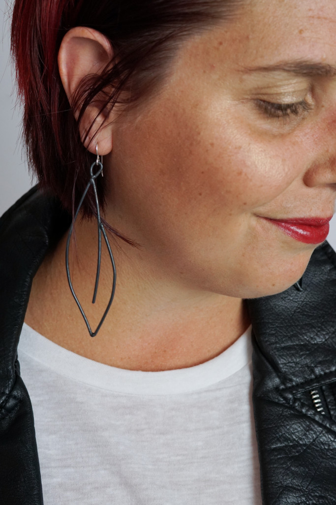 black statement earrings with leather jacket, white t-shirt, and bold red lip