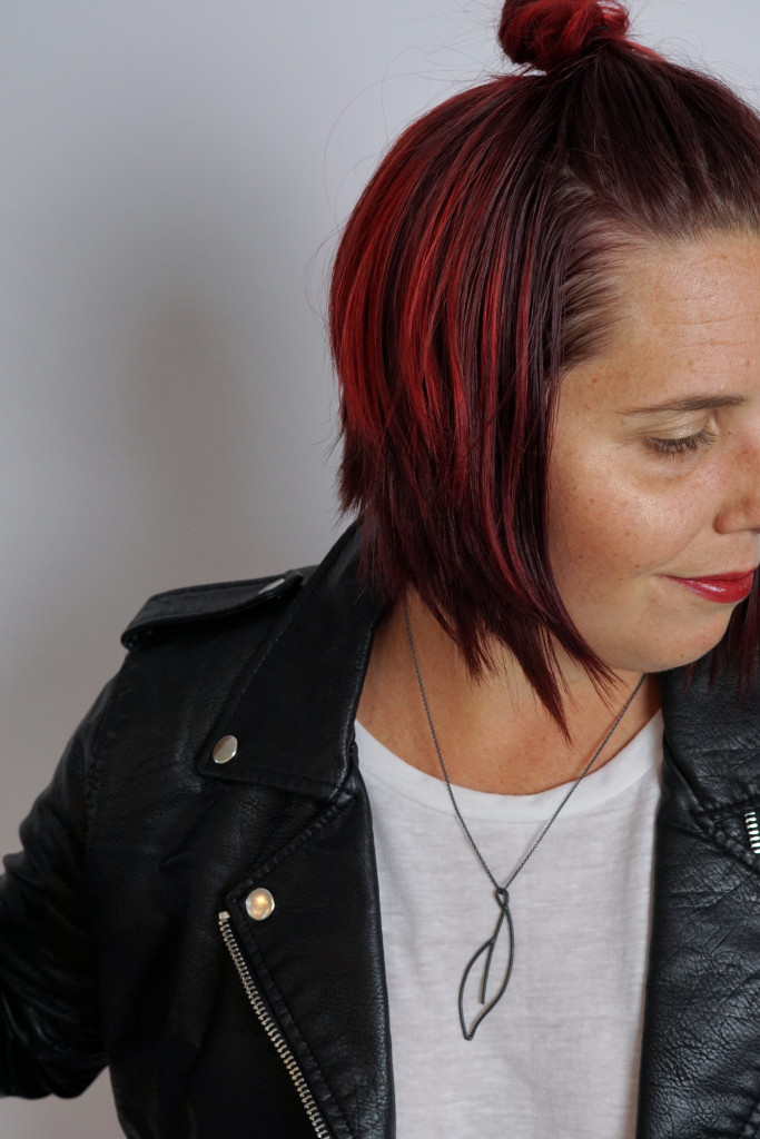 black necklace with a bold lip, white t-shirt, and leather jacket