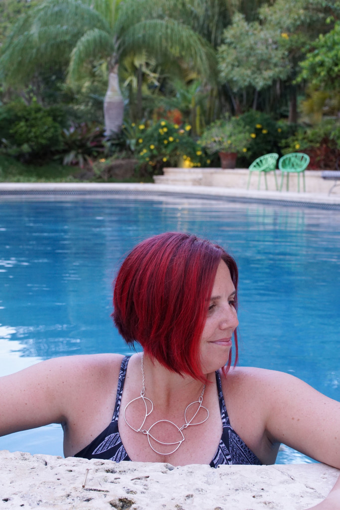artist and metalsmith Megan Auman wearing a silver statement necklace in the pool at Golden Rock Inn Nevis, West Indies