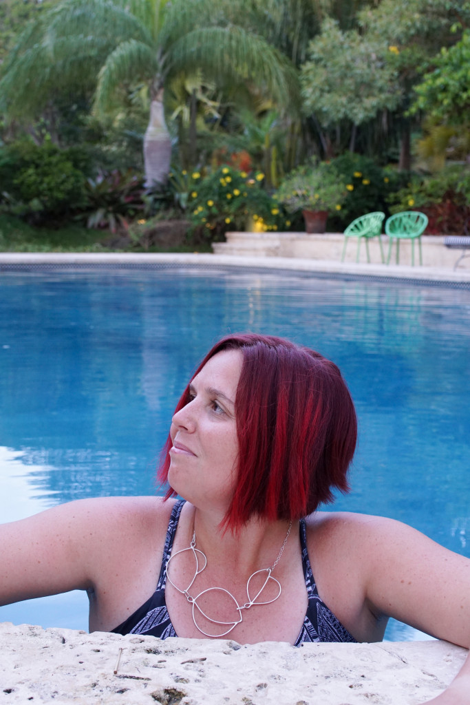 artist and metalsmith Megan Auman wearing a silver statement necklace in the pool at Golden Rock Inn Nevis, West Indies