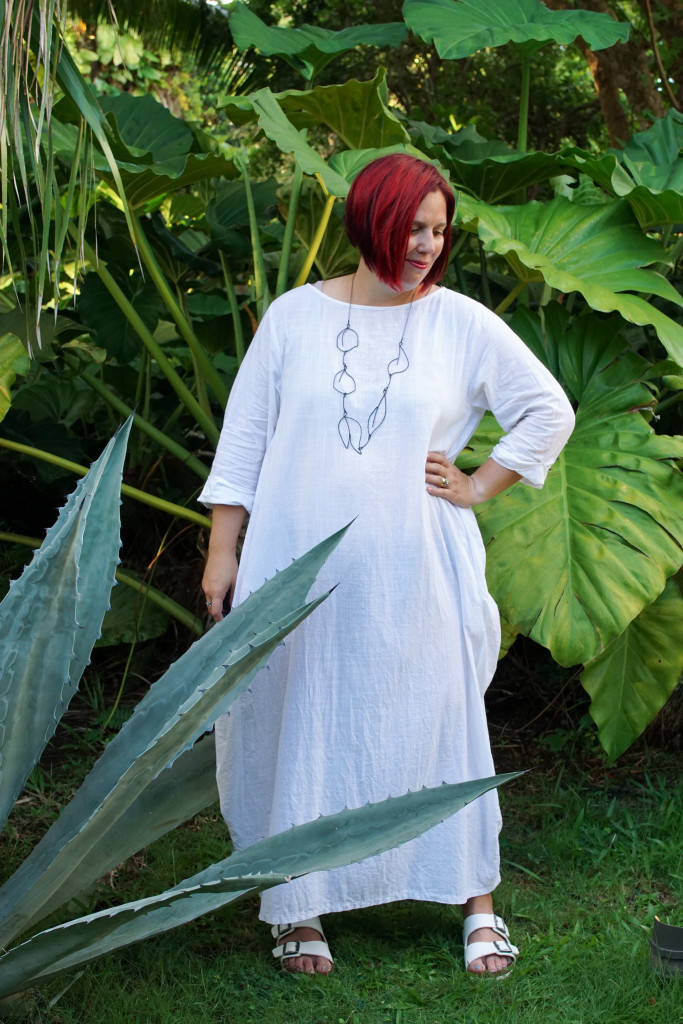 white dress and black statement necklace in the garden at Golden Rock Inn Nevis