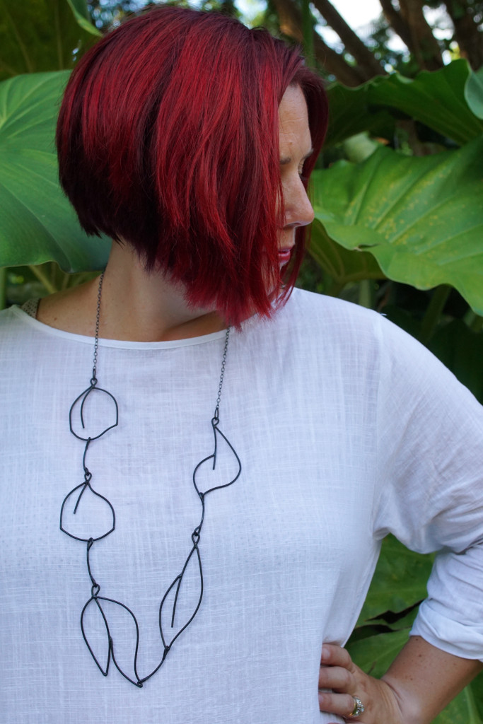 white dress and black statement necklace in the garden at Golden Rock Inn Nevis