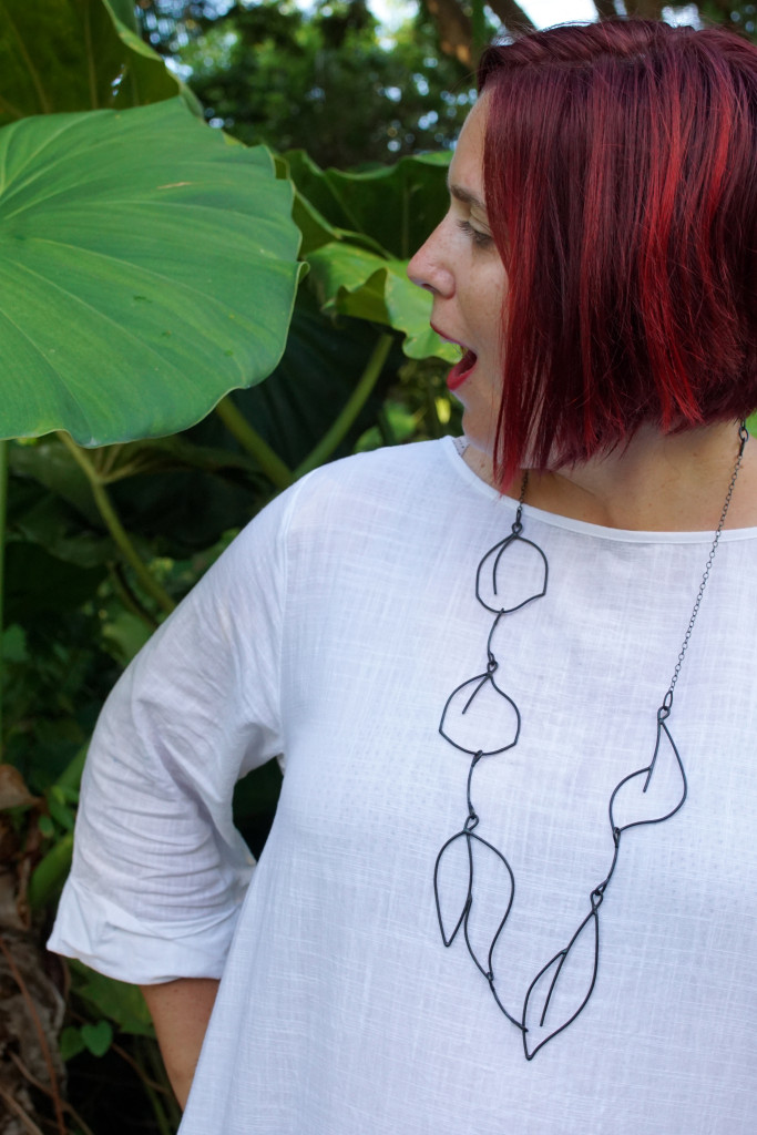 white dress and black statement necklace in the garden at Golden Rock Inn Nevis