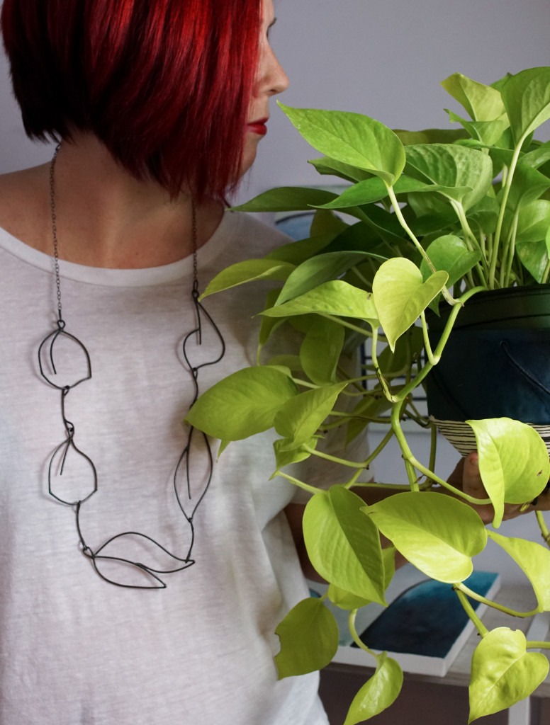 neon pothos, handmade ceramic planter, and contemporary necklace made and modeled by metalsmith Megan Auman