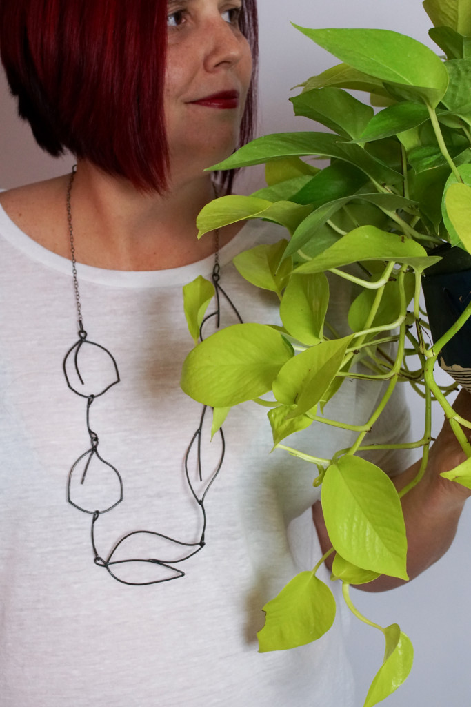 neon pothos, handmade ceramic planter, and contemporary necklace made and modeled by metalsmith Megan Auman