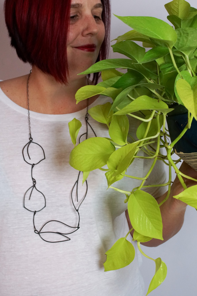 neon pothos, handmade ceramic planter, and contemporary necklace made and modeled by metalsmith Megan Auman