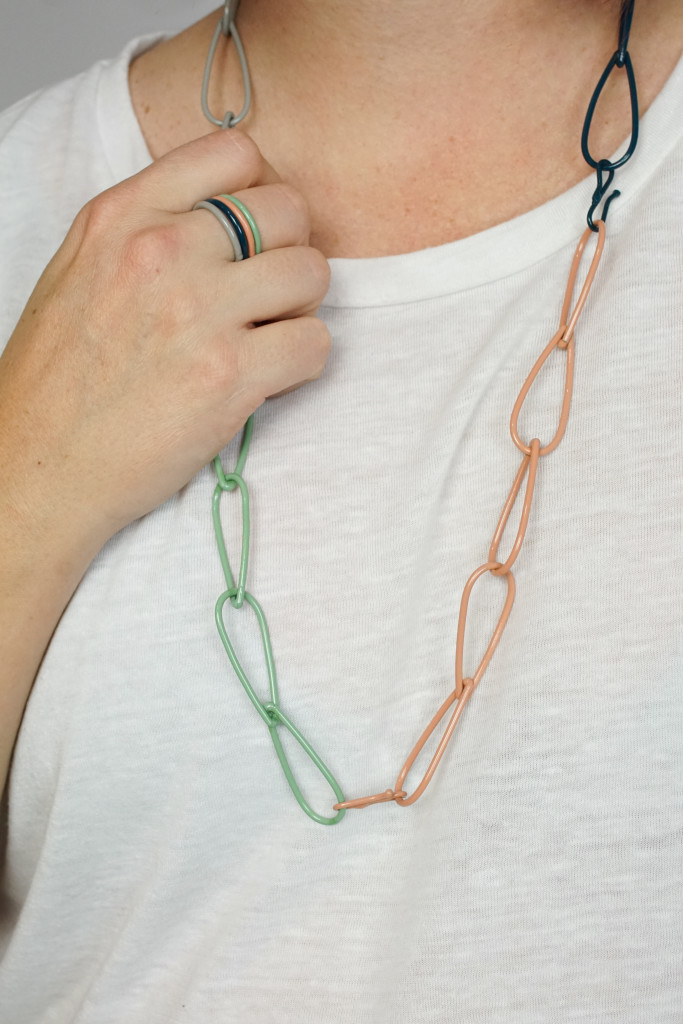 colorful jewelry: stacking rings and modern chain necklace on a white t-shirt