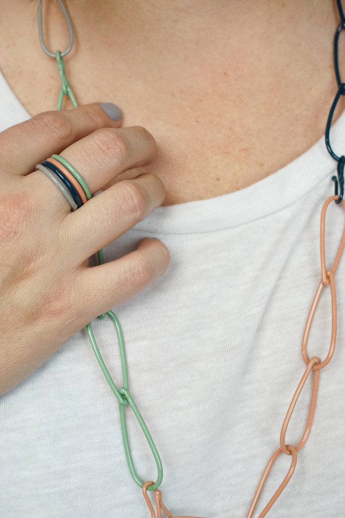 colorful jewelry: stacking rings and modern chain necklace on a white t-shirt