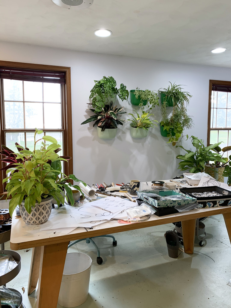 living plant wall behind artist, metalsmith's work table