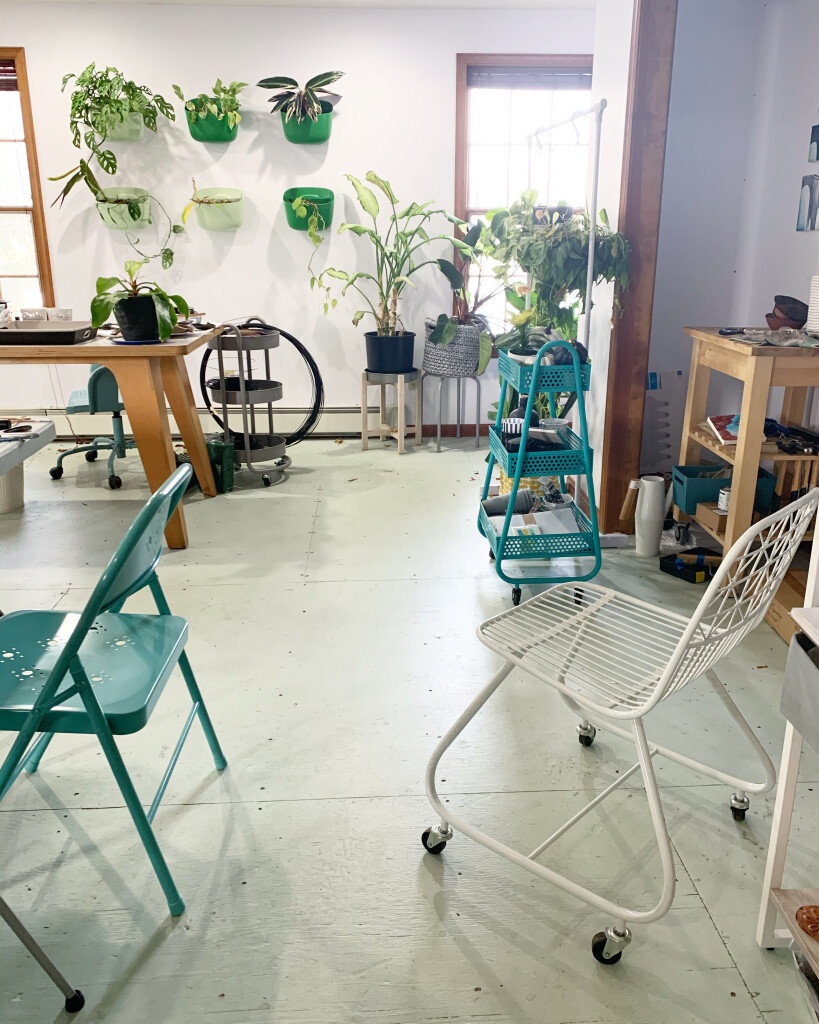 artist studio with painted floors, metal chairs, plants, and rolling metal storage carts