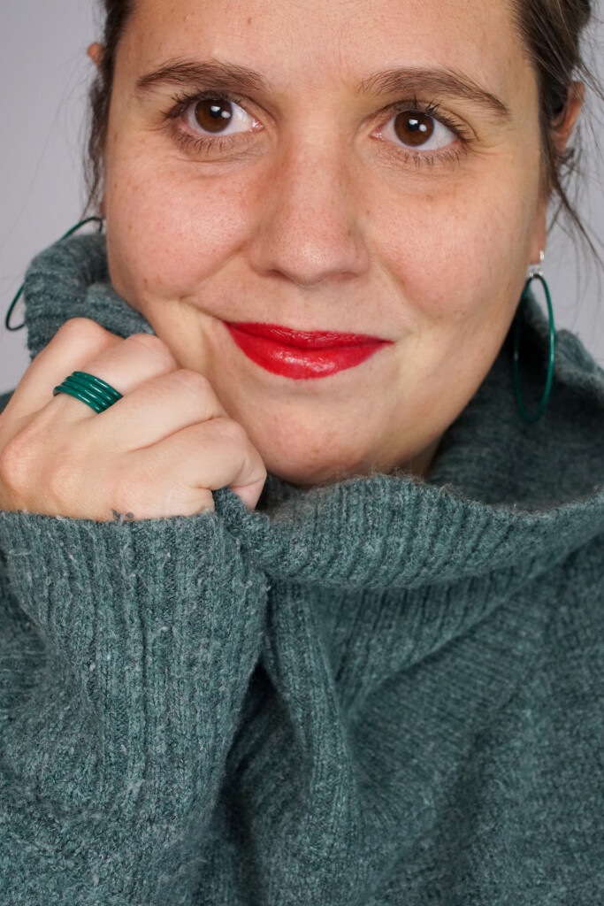 casual low key holiday style: bold lip, cozy sweater, emerald green jewelry