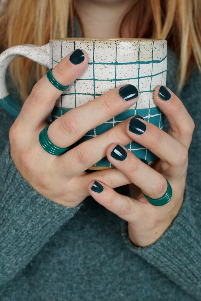 cozy fall holiday winter style: handmade mug, green stacking rings, and chunky sweater