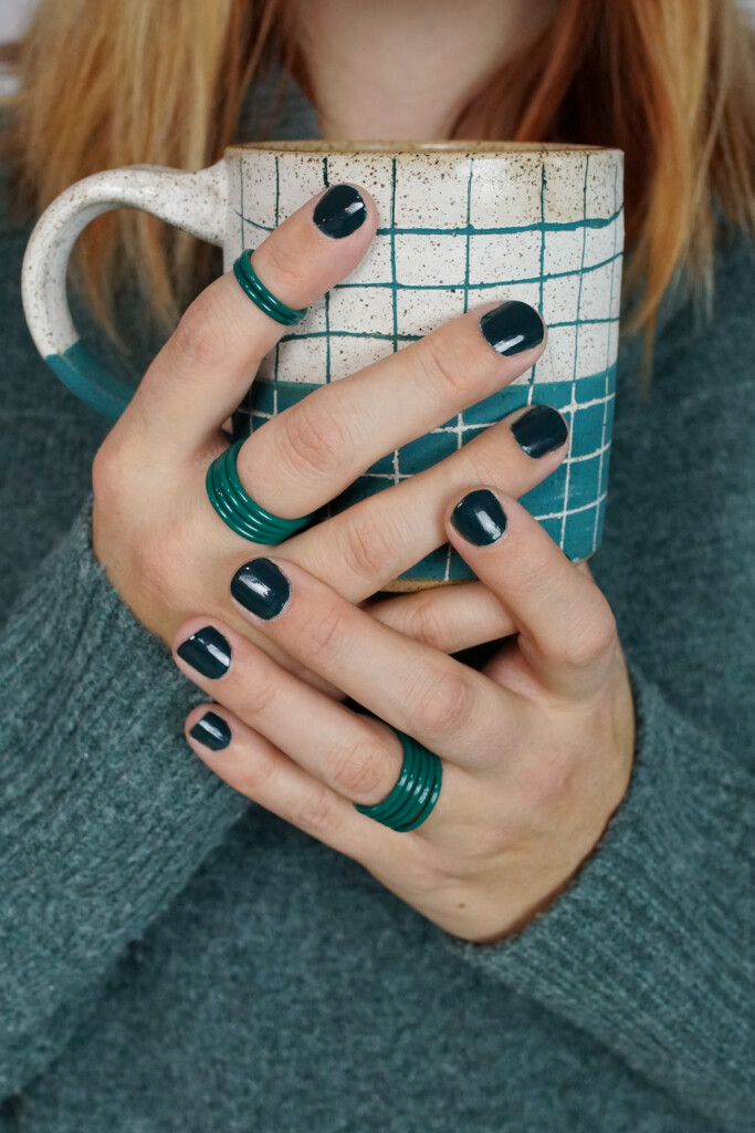 cozy fall holiday winter style: handmade mug, green stacking rings, and chunky sweater