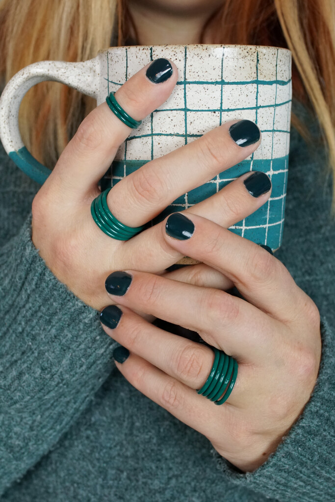 cozy fall holiday winter style: handmade mug, green stacking rings, and chunky sweater