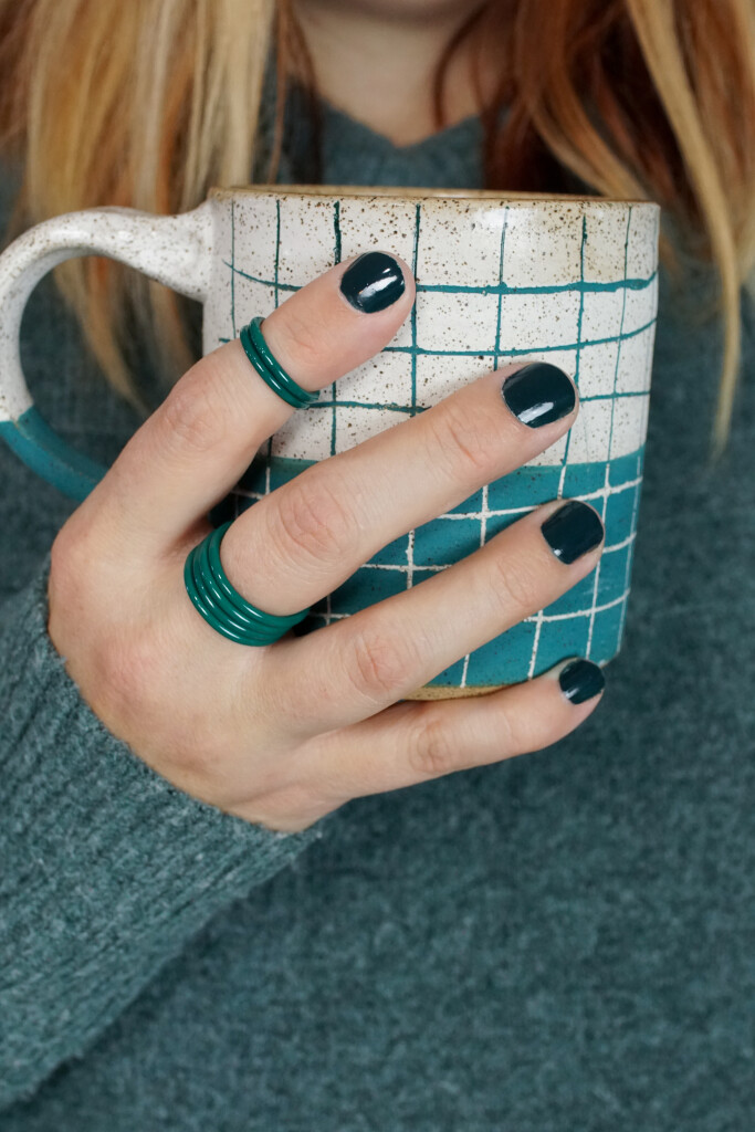 cozy fall holiday winter style: handmade mug, green stacking rings, and chunky sweater