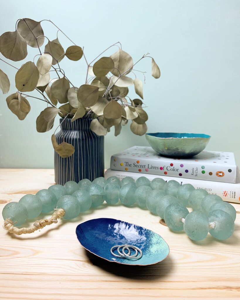 nightstand styling - colorful copper ring dish and bowl, glass beads, vase, books