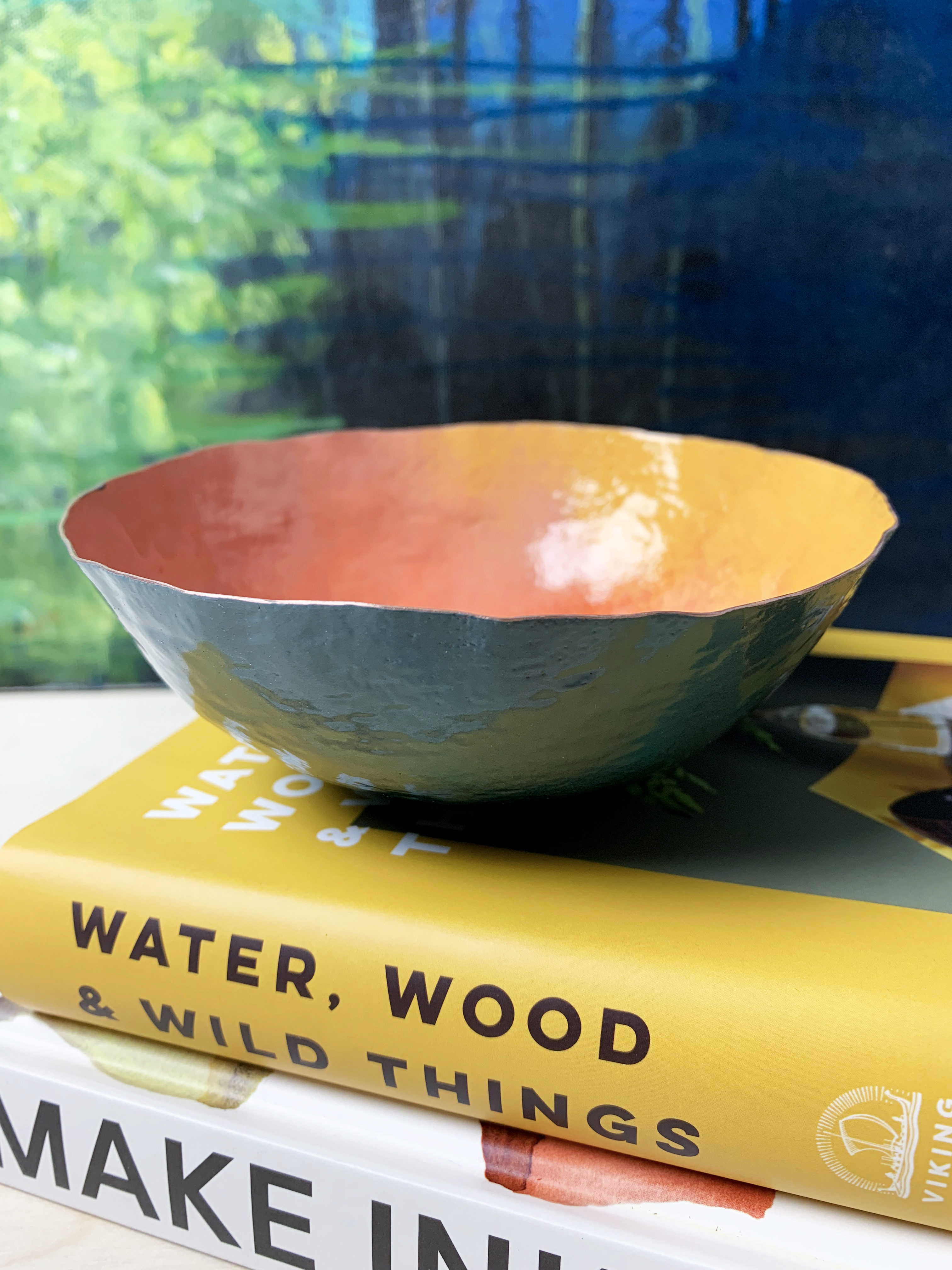 colorful hand-hammered copper bowl with painting and books on craft