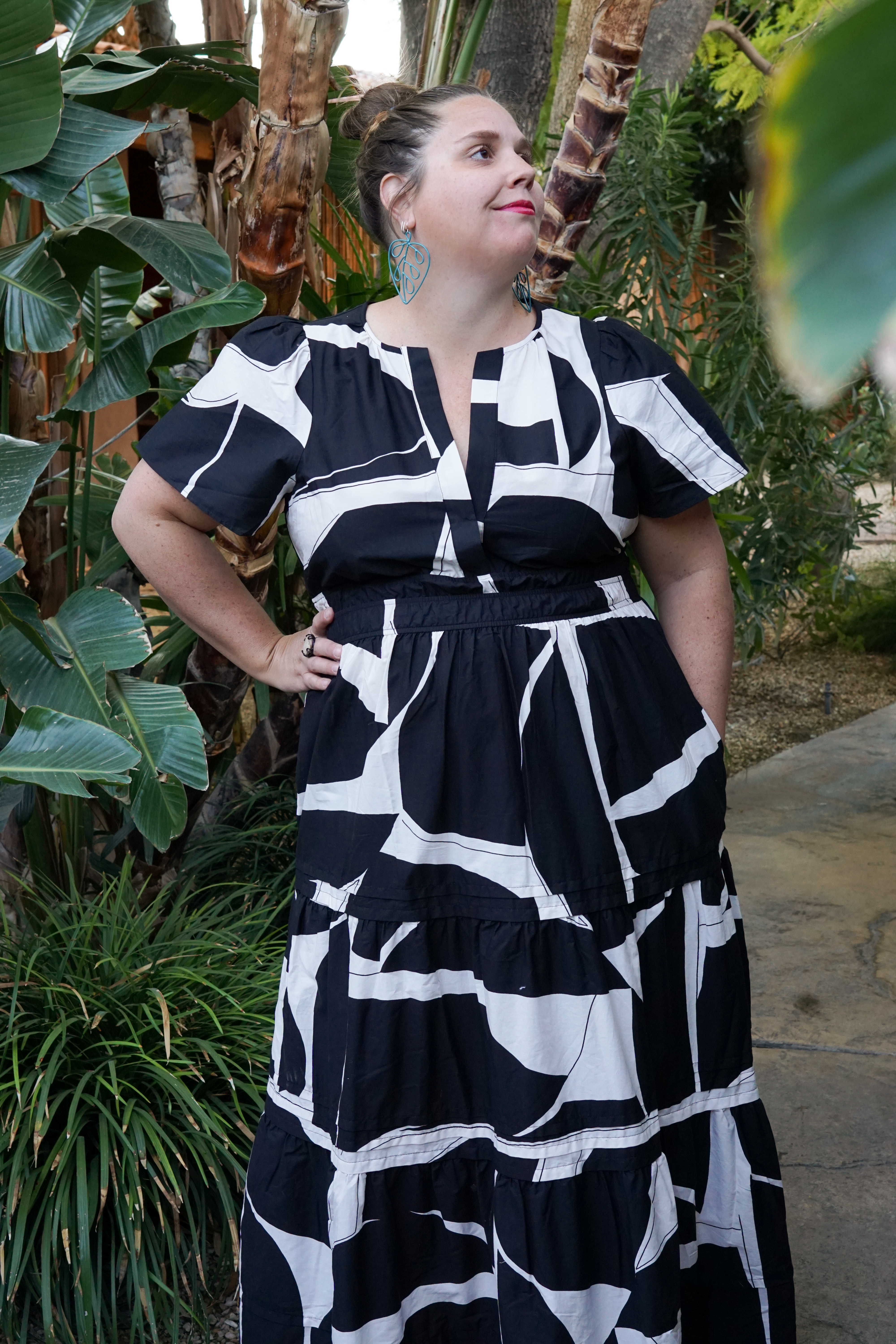 woman wearing black and white dress and statement earrings in a garden in palm springs, california