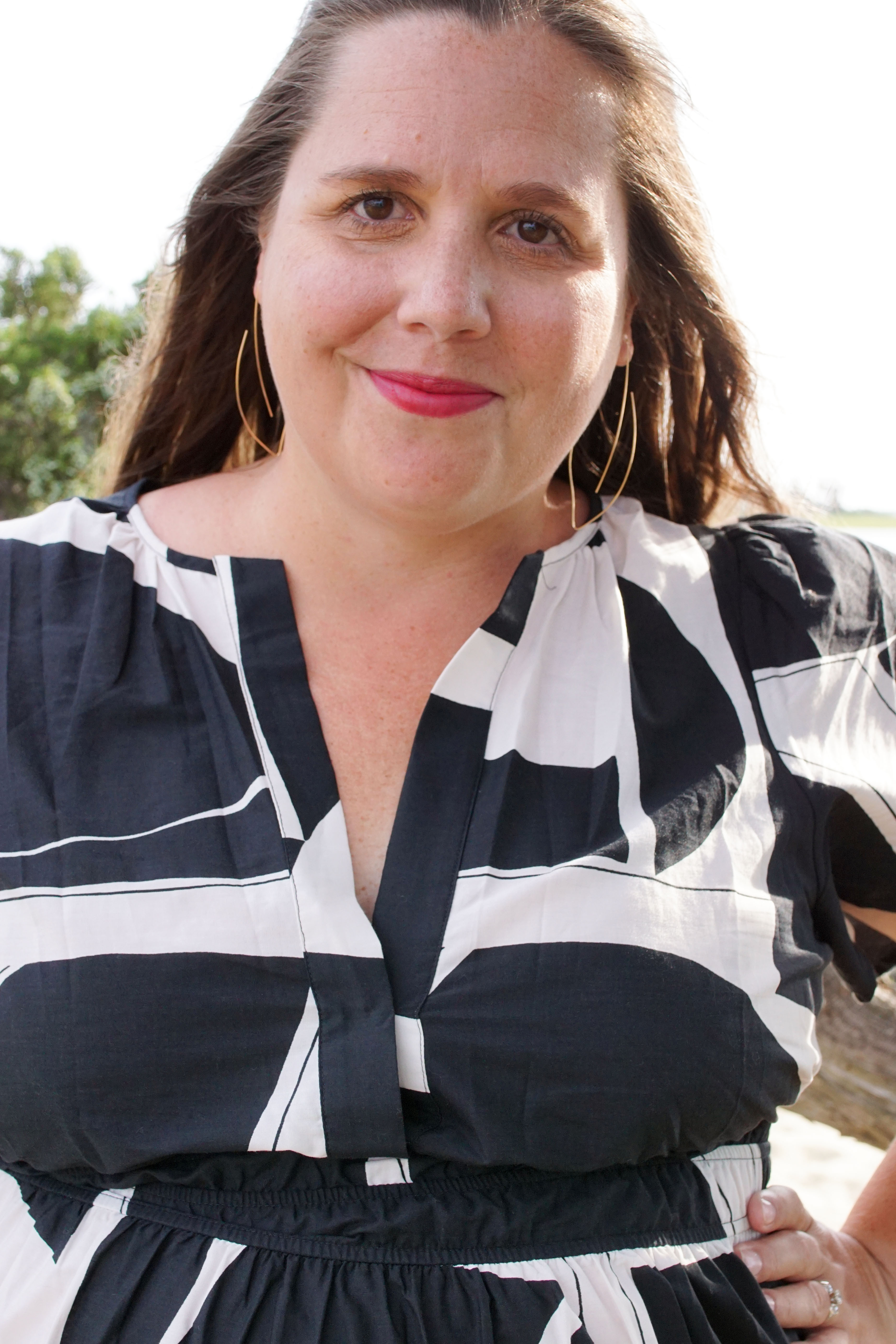 woman wearing black and white dress on a beach with gold threader hoop earrings