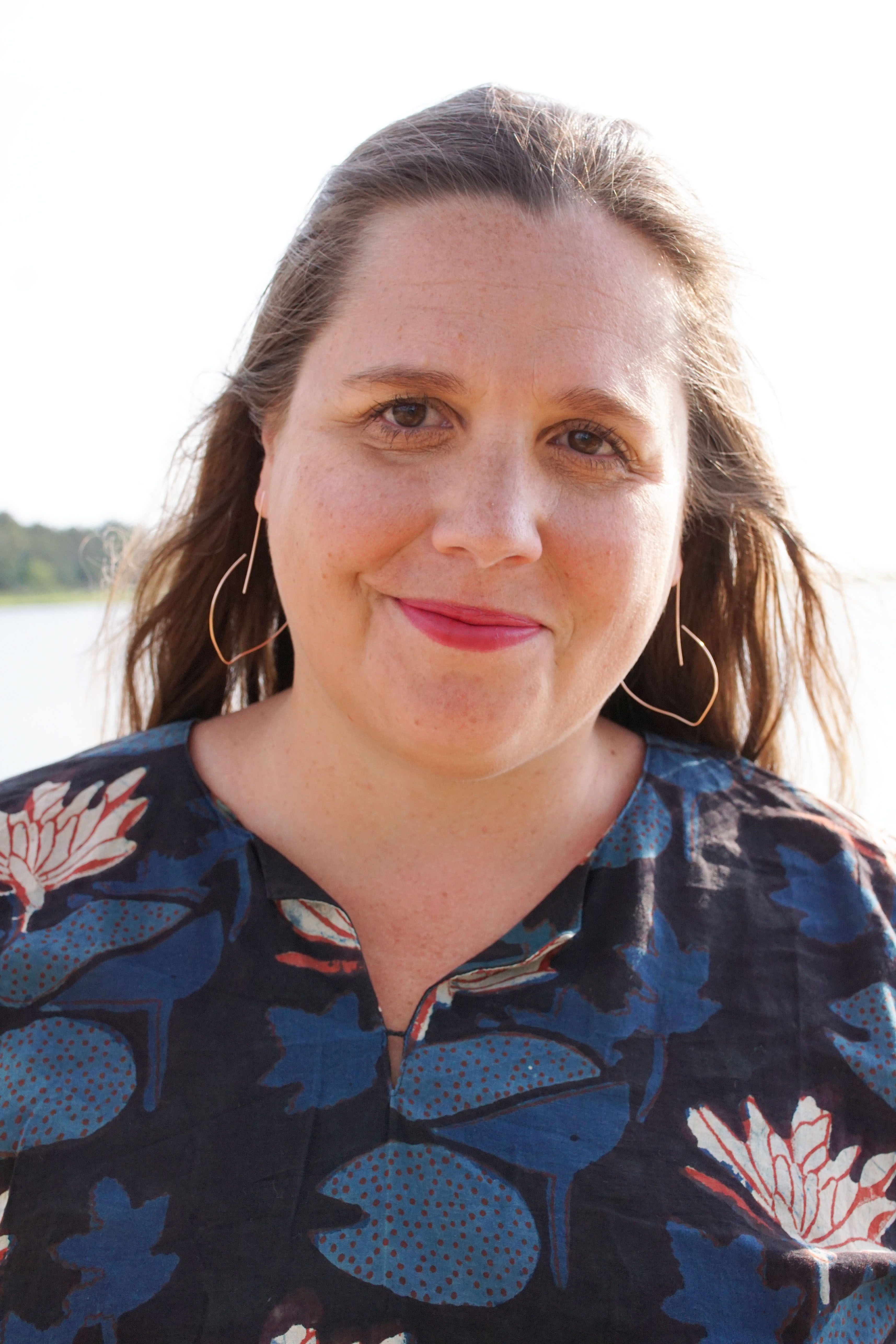 portrait of woman wearing block-printed kaftan and rose gold threader hoop earrings at the beach