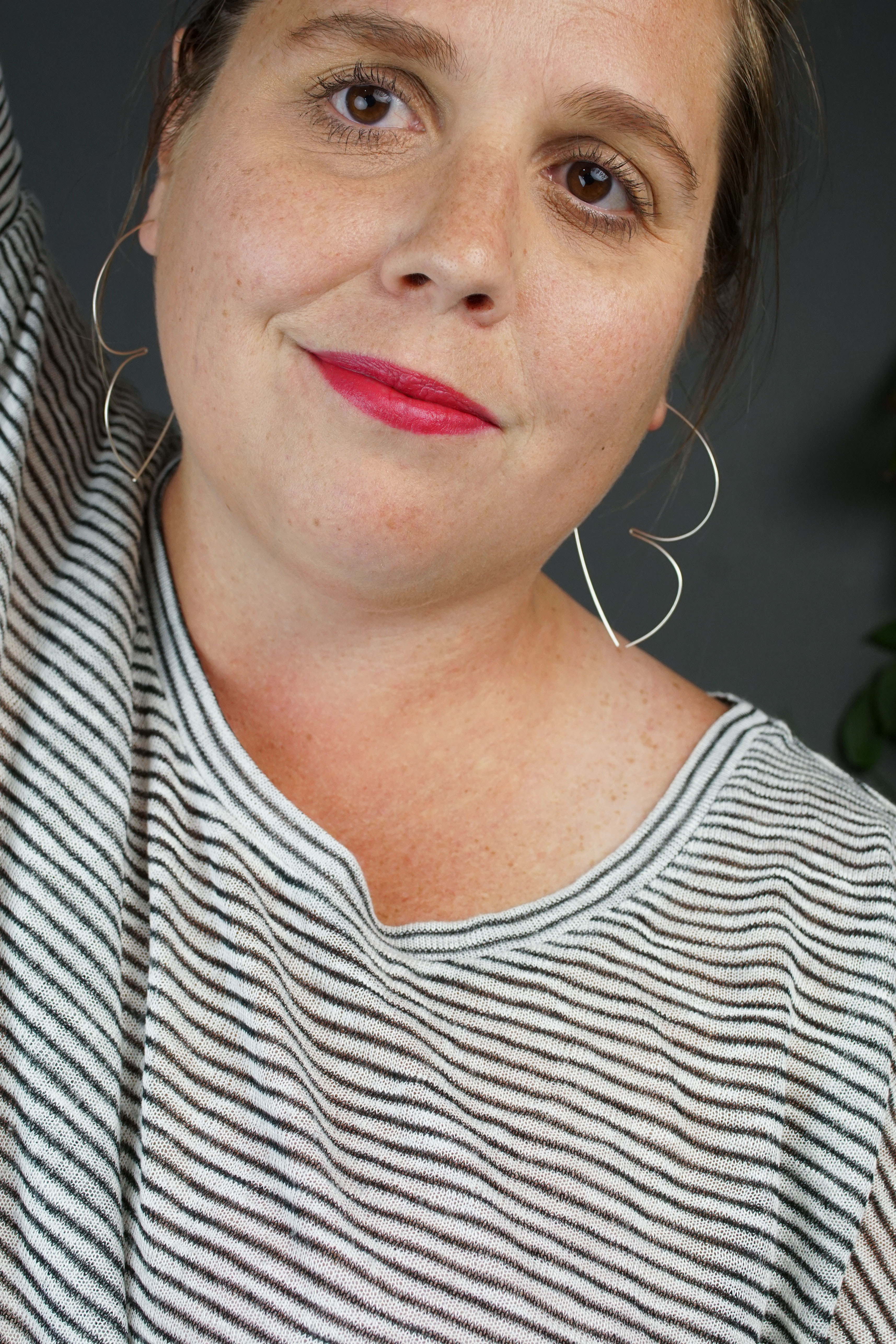 portrait of a woman with a bold red lip wearing a striped shirt and silver threader hoop earrings