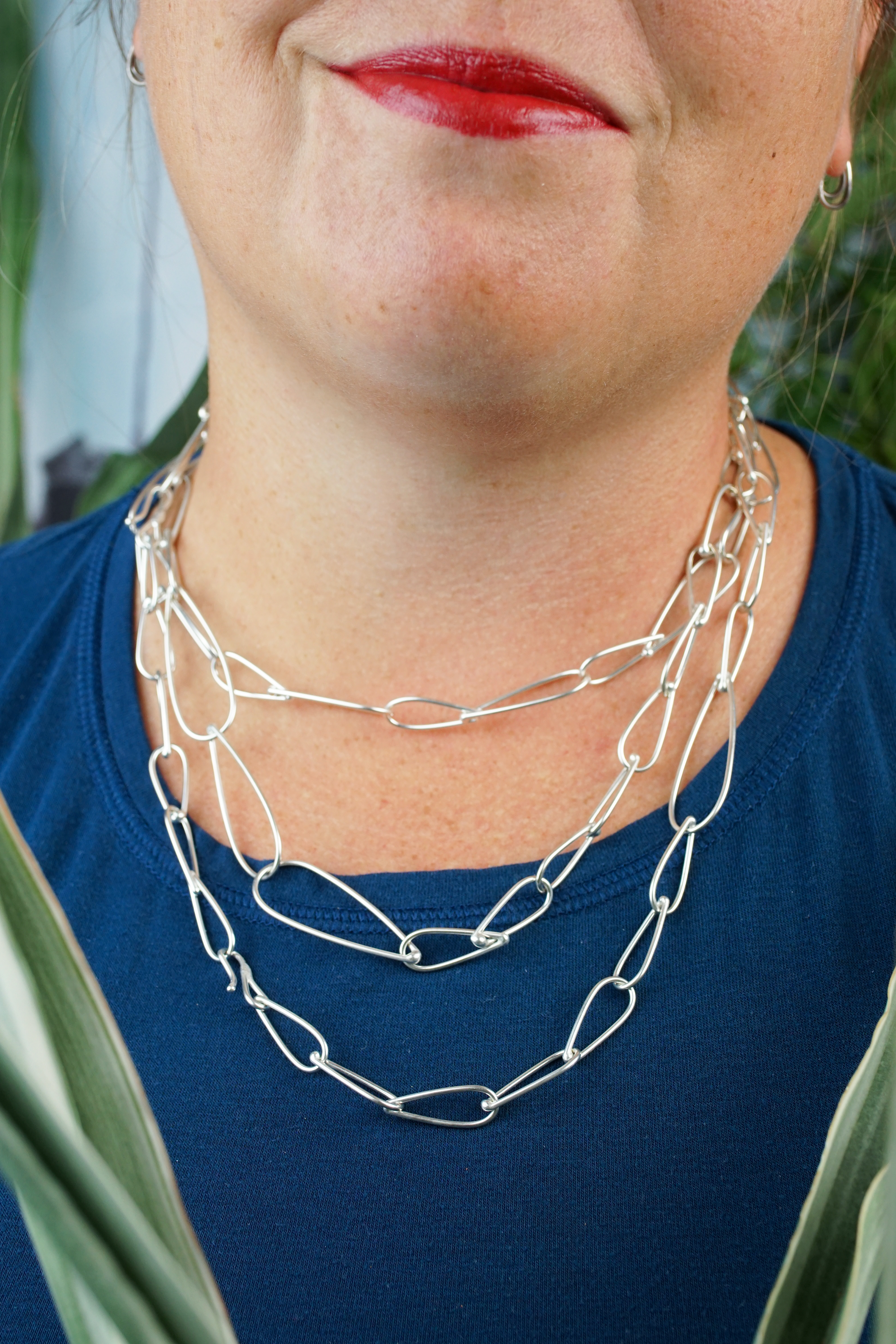 layered necklaces: woman wearing silver chain necklaces of three different lengths