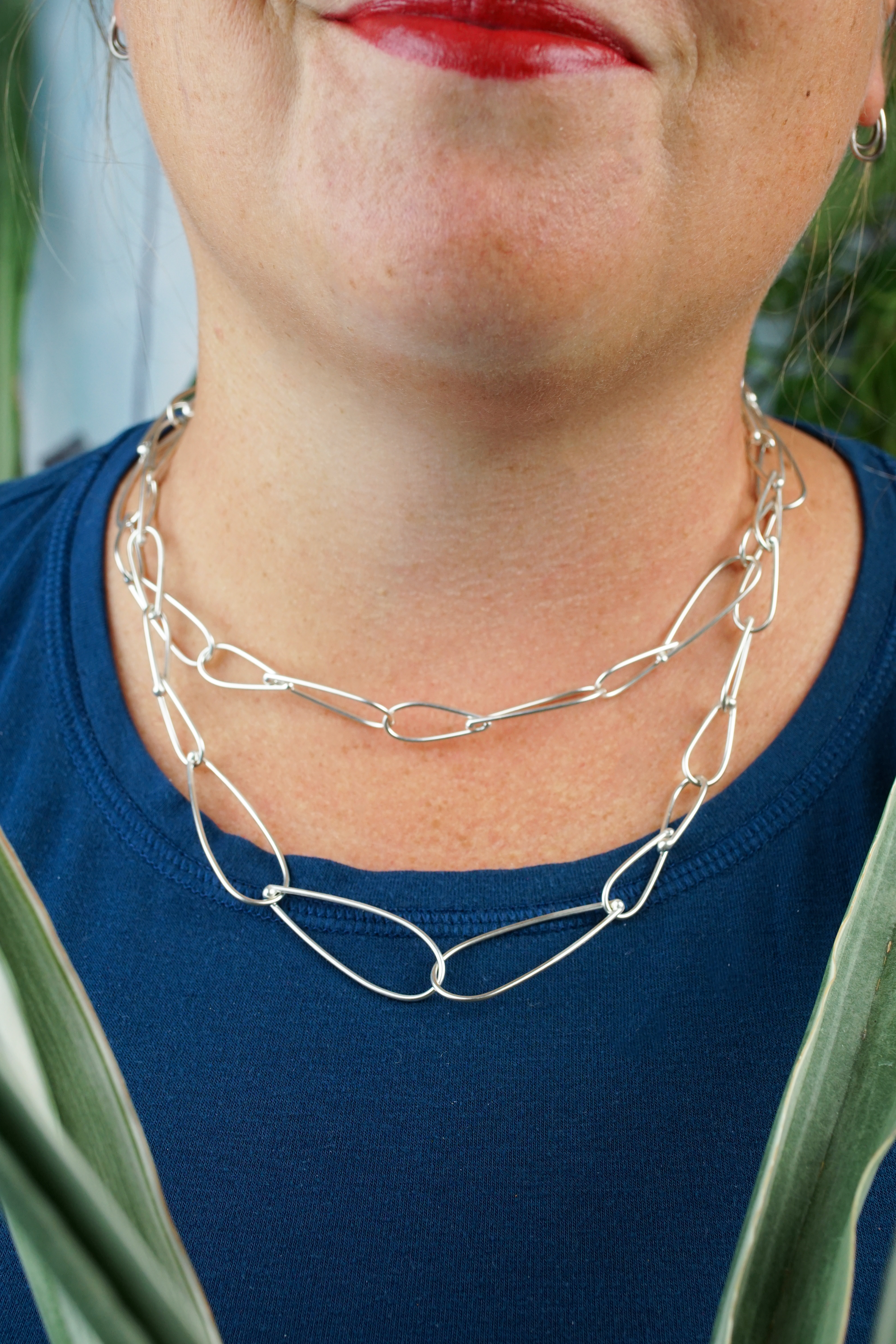 layered necklaces: woman wearing silver chain necklaces of two different lengths