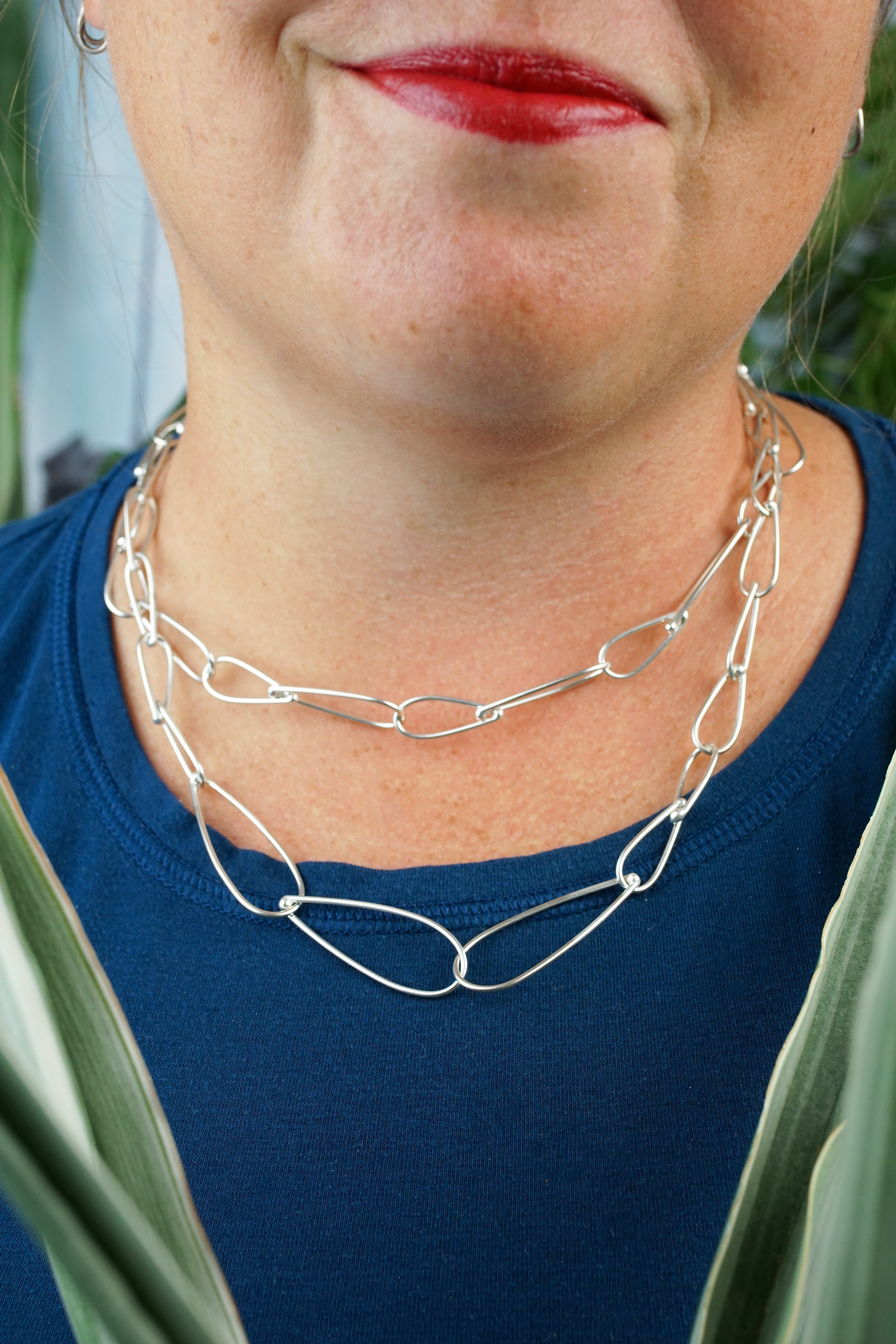 layered necklaces: woman wearing silver chain necklaces of two different lengths