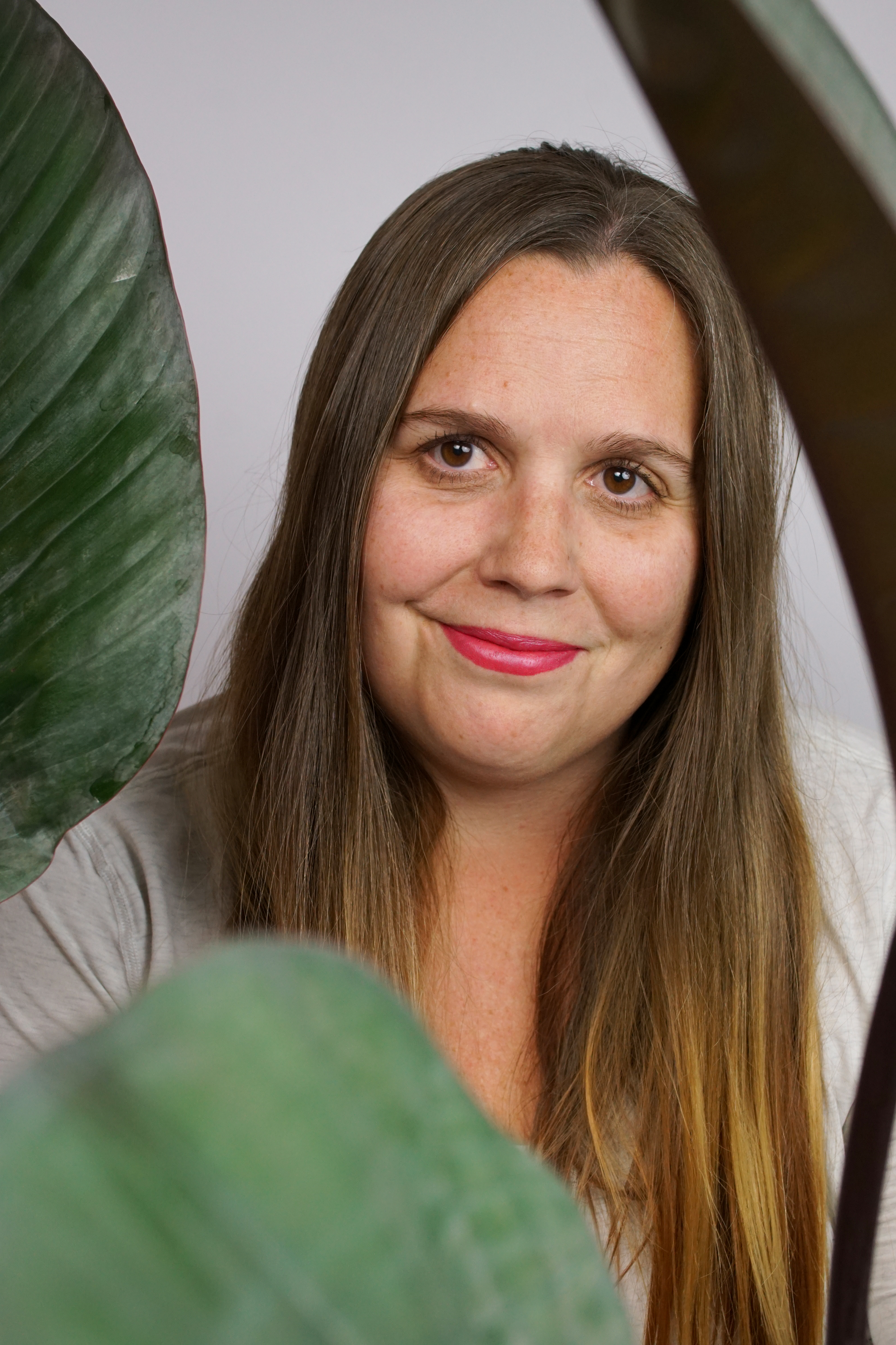 self-portrait of woman with long hair and house plant: philodendron rojo congo