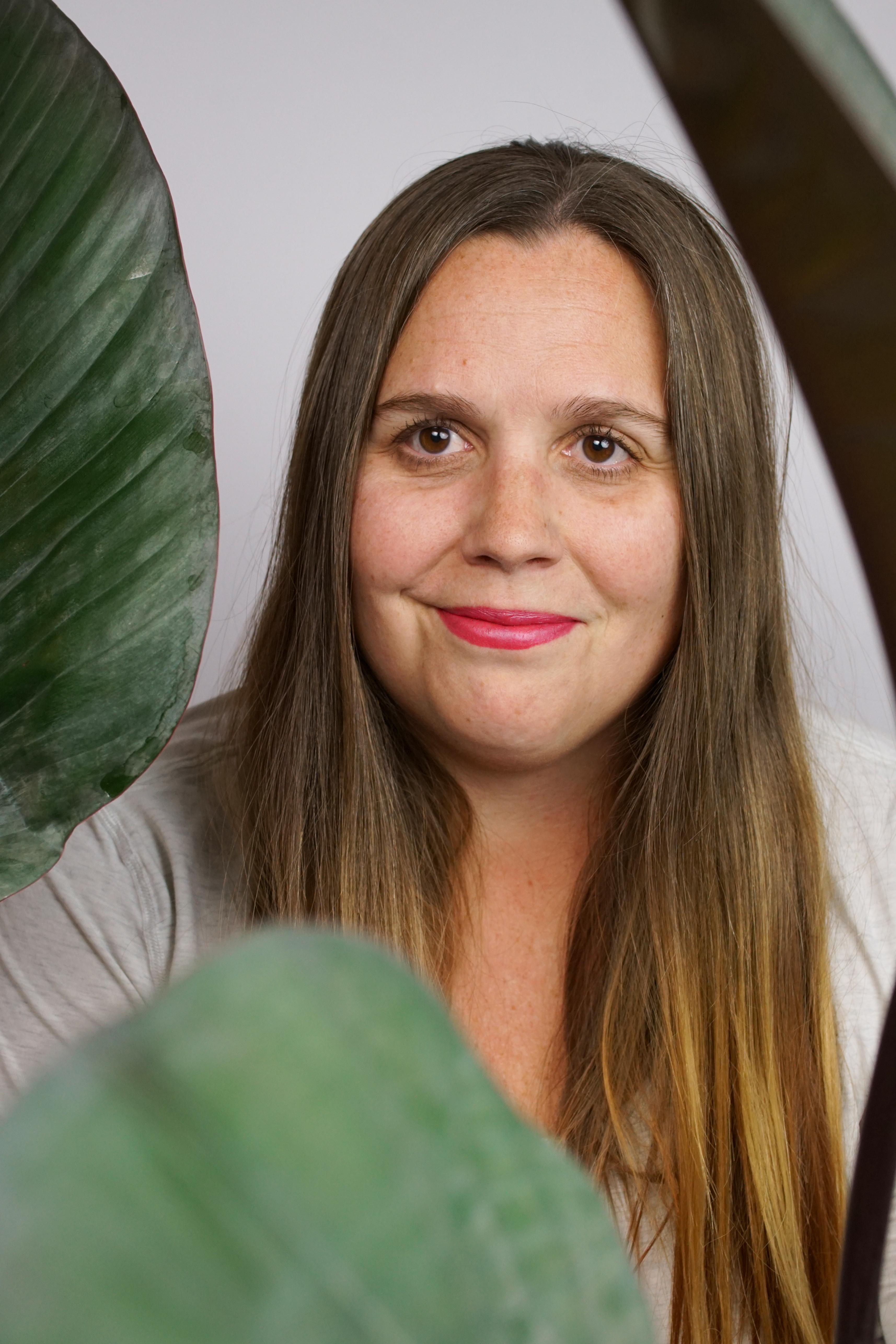 self-portrait of woman with long hair and house plant: philodendron rojo congo