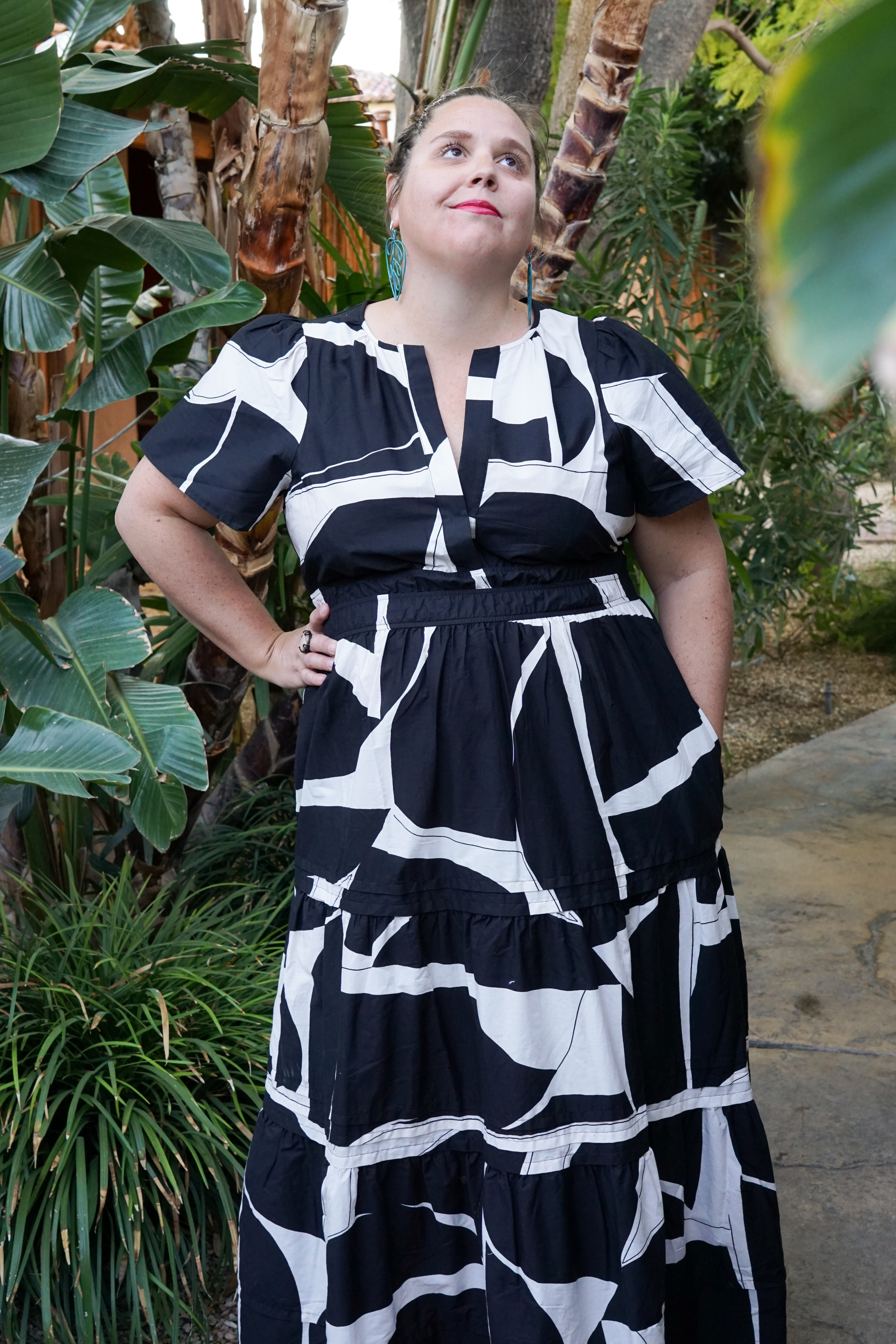 woman wearing black and white dress and statement earrings in a garden in palm springs, california