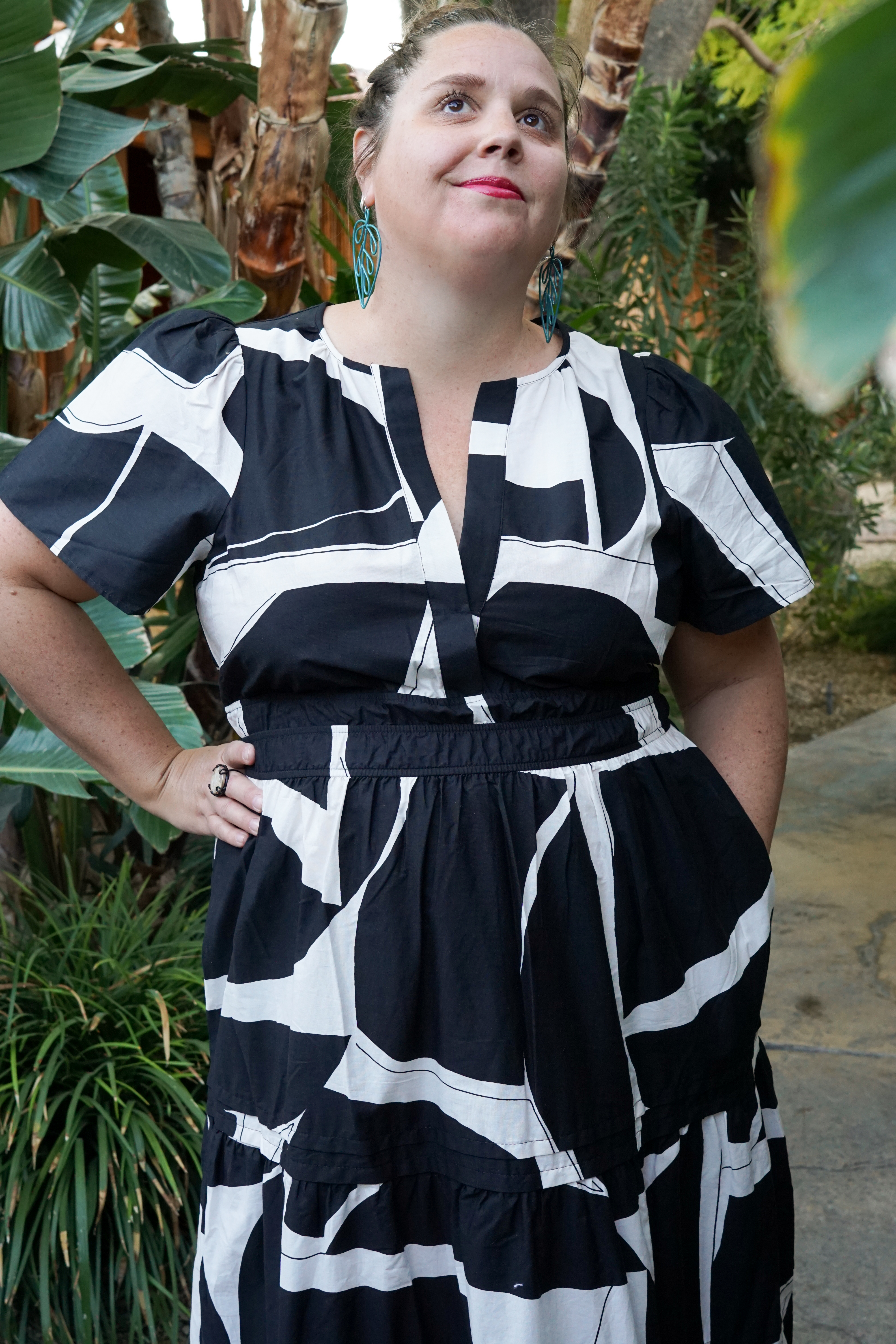 woman wearing black and white dress and statement earrings in a garden in palm springs, california