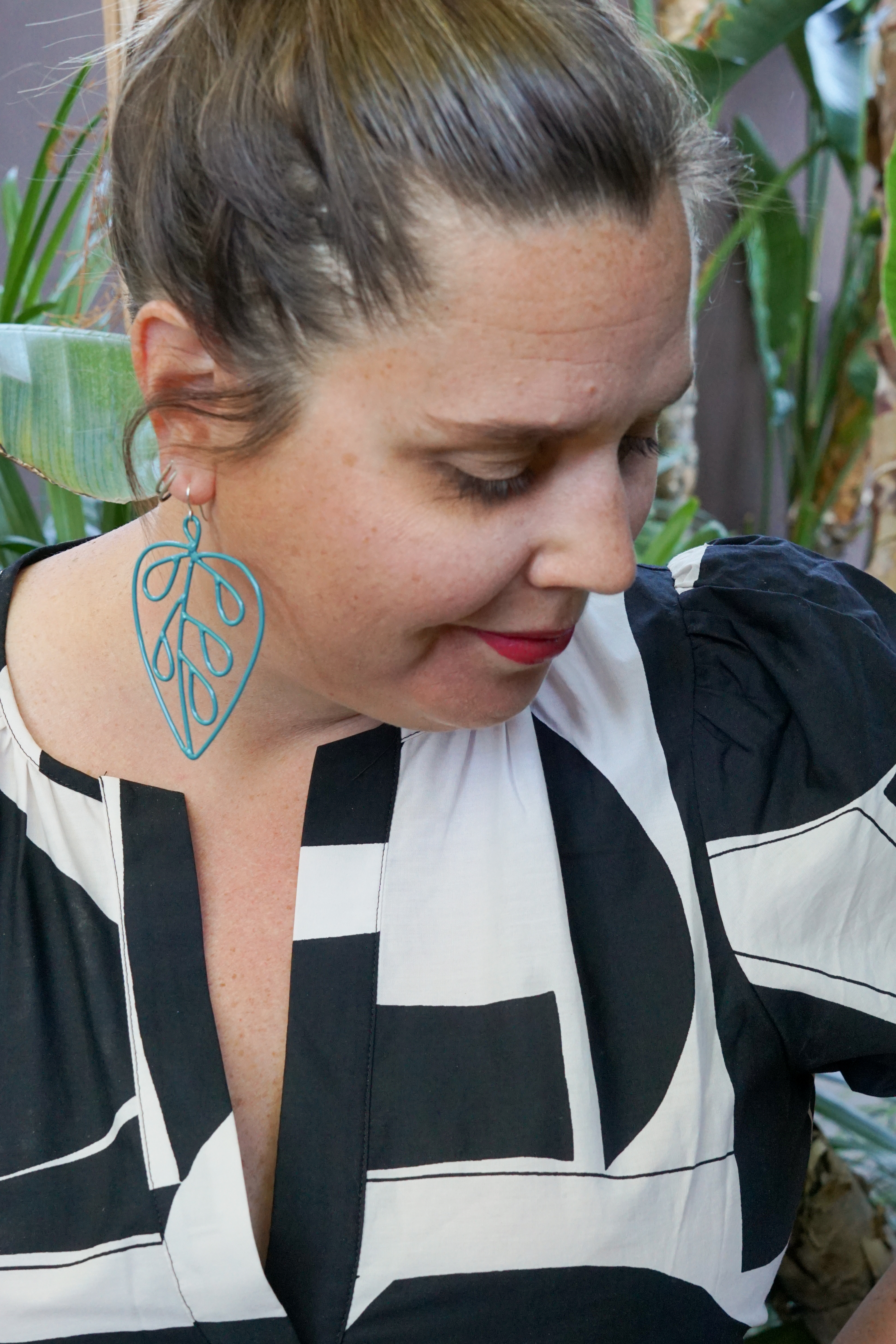 woman wearing black and white dress and statement earrings in a garden in palm springs, california