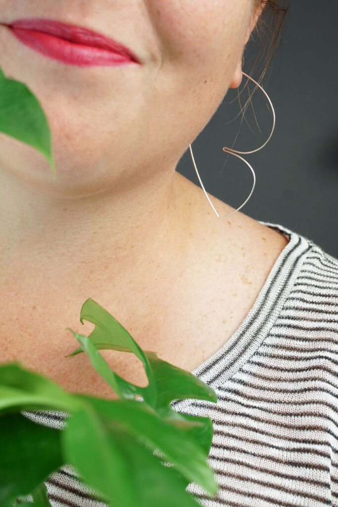 woman wearing unique silver threader hoop earrings and a striped shirt