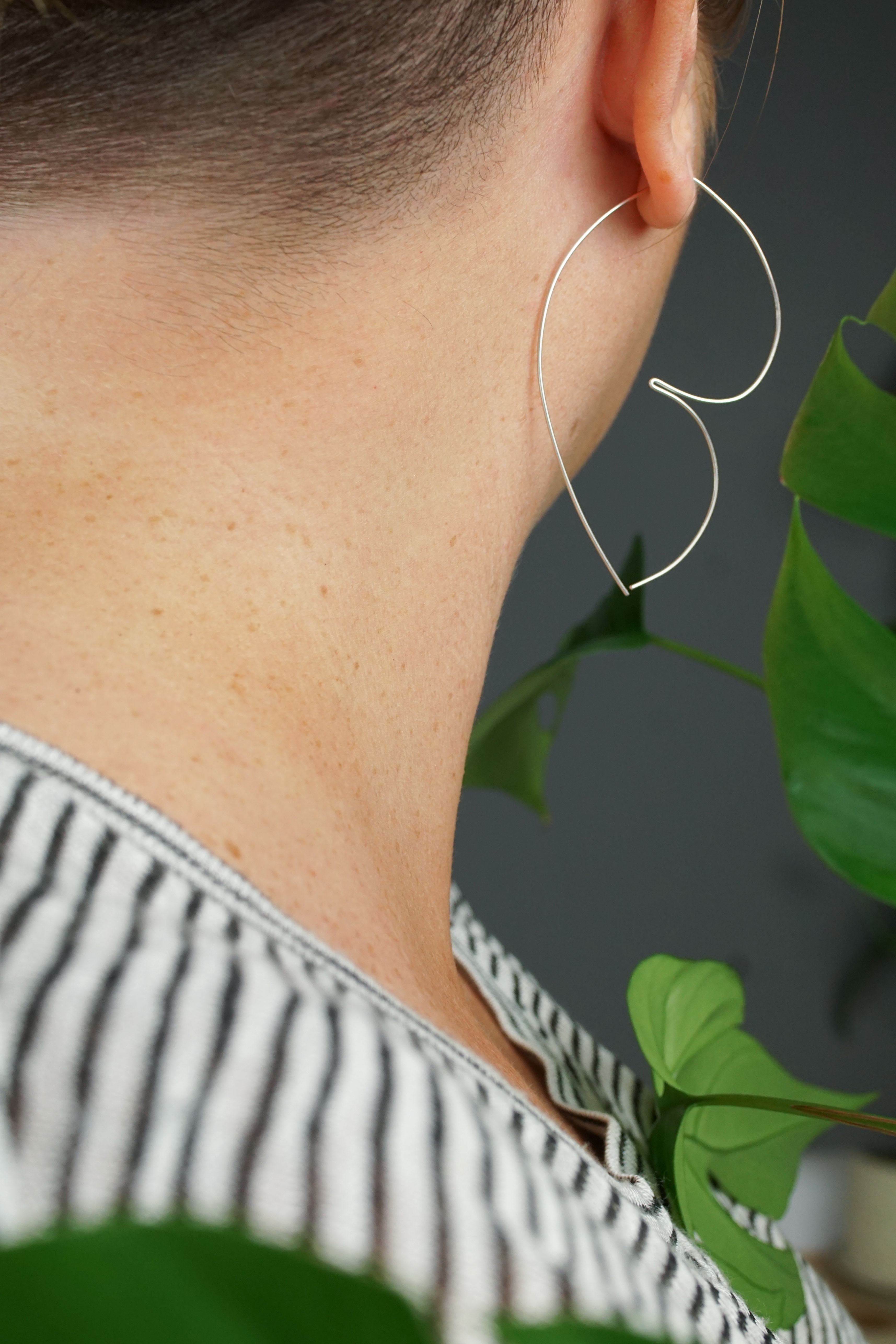 woman wearing unique silver threader hoop earrings and a striped shirt