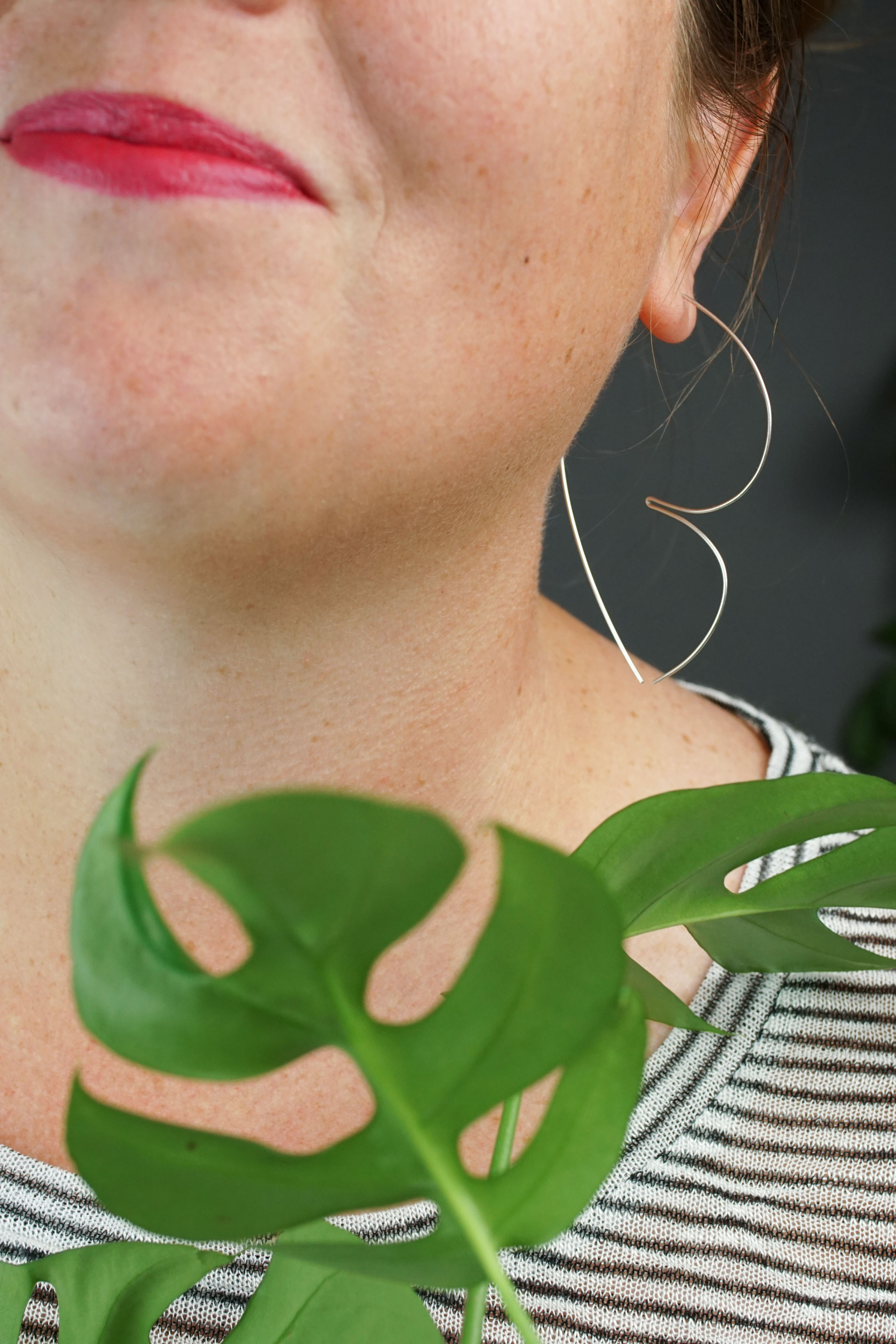 woman wearing unique silver threader hoop earrings and a striped shirt