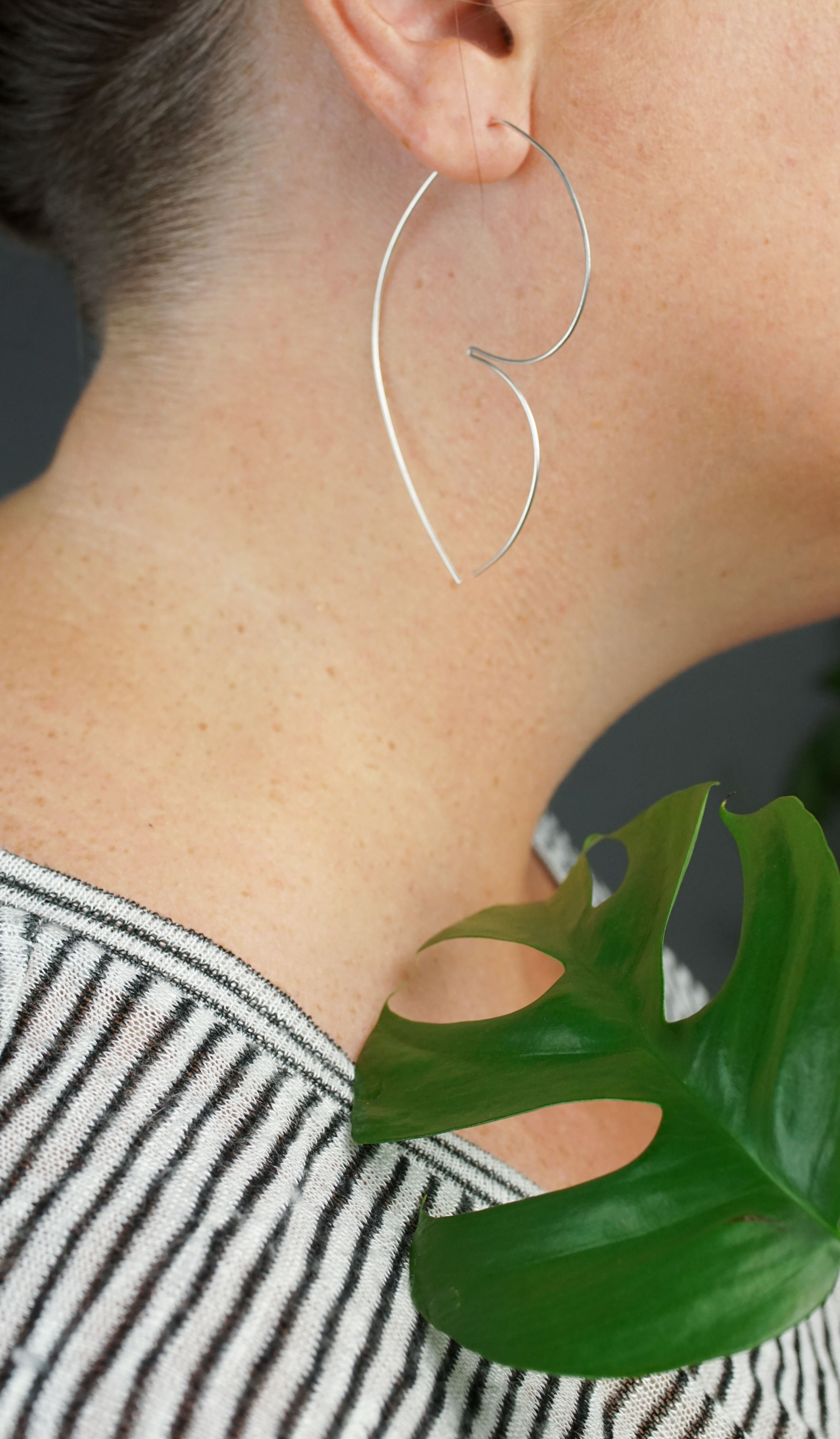 woman wearing unique silver threader hoop earrings and a striped shirt