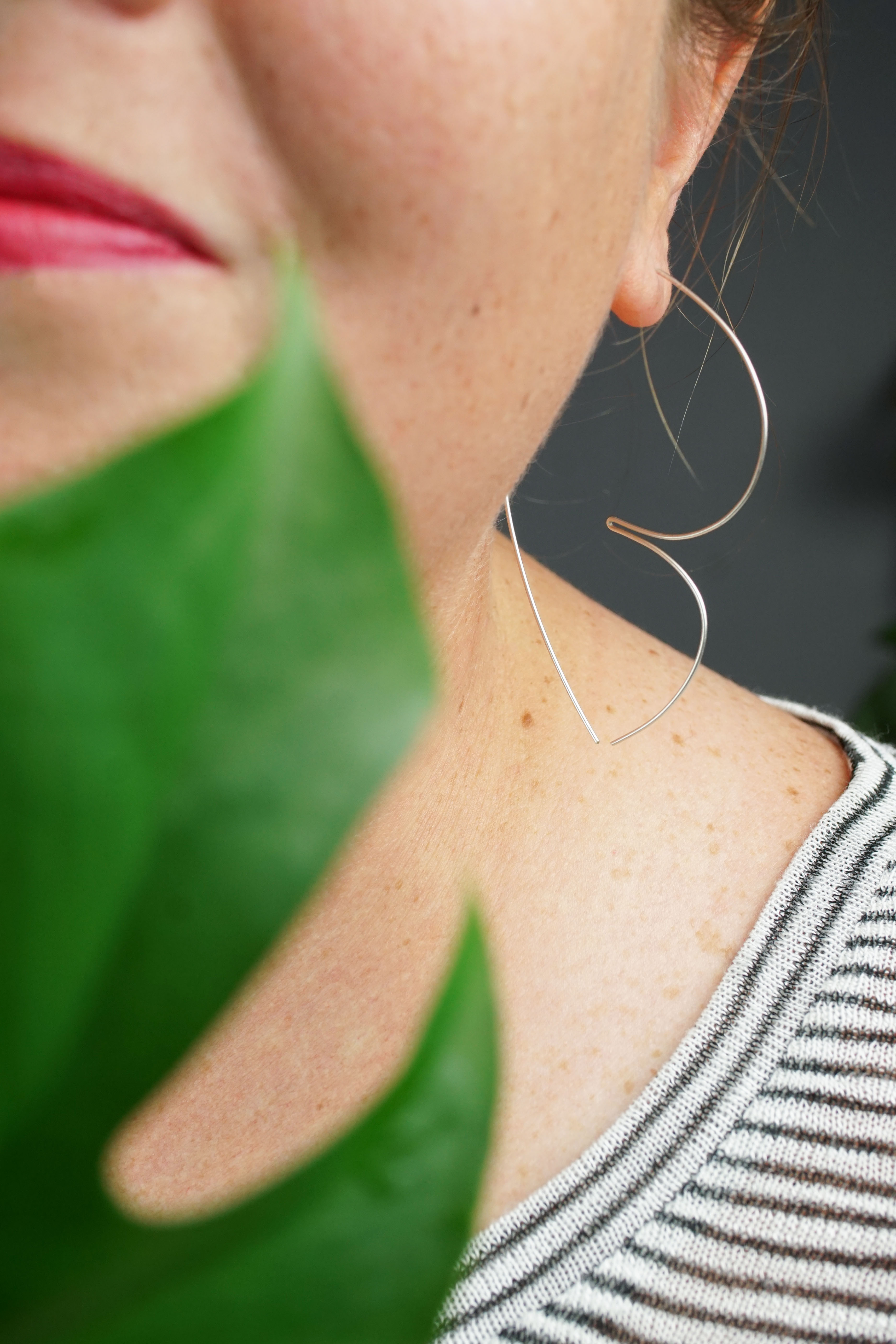 woman wearing unique silver threader hoop earrings and a striped shirt