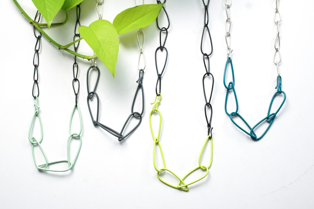 colorful and neon chain link necklaces with silver and steel and a neon pothos