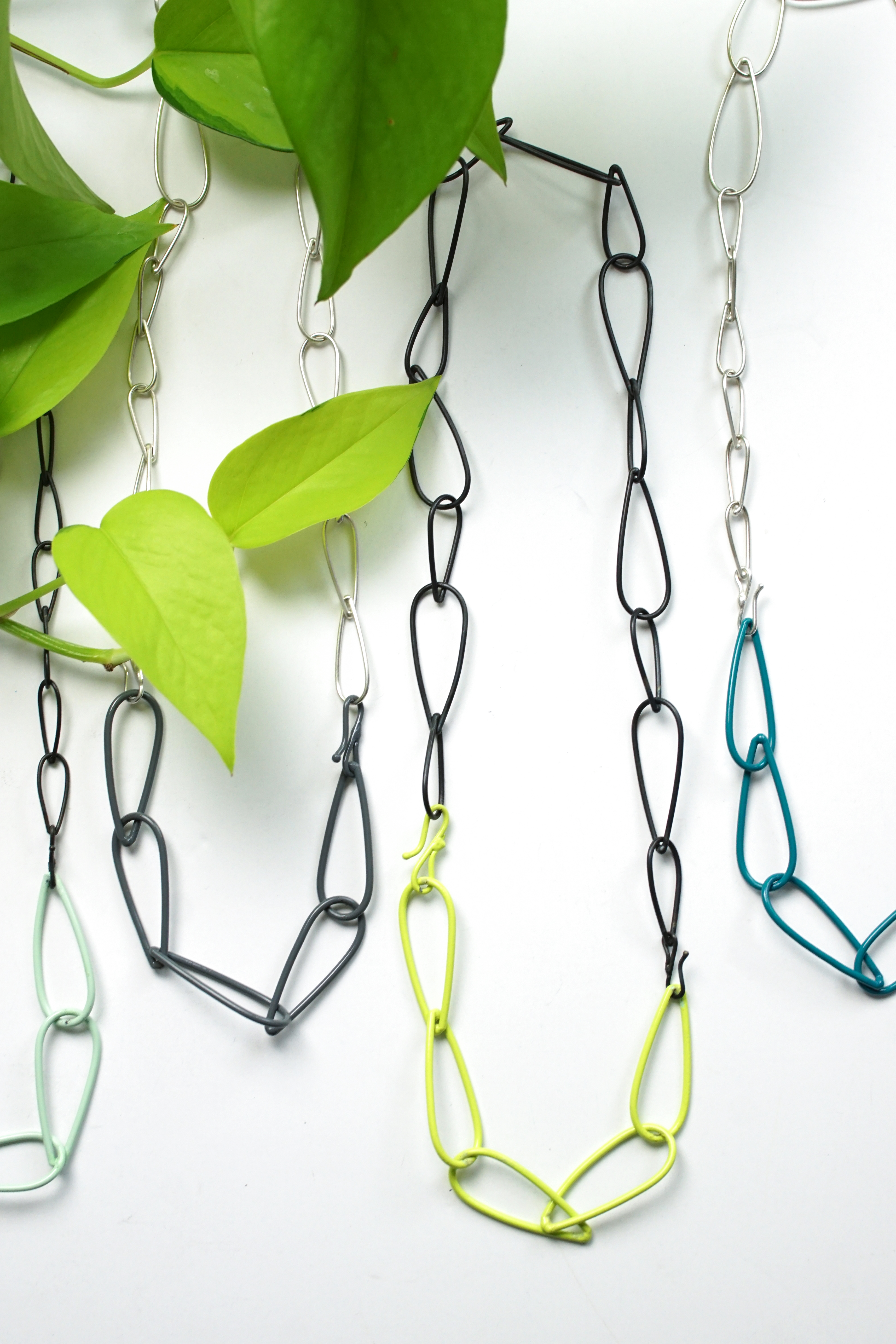 colorful and neon chain link necklaces with silver and steel and a neon pothos