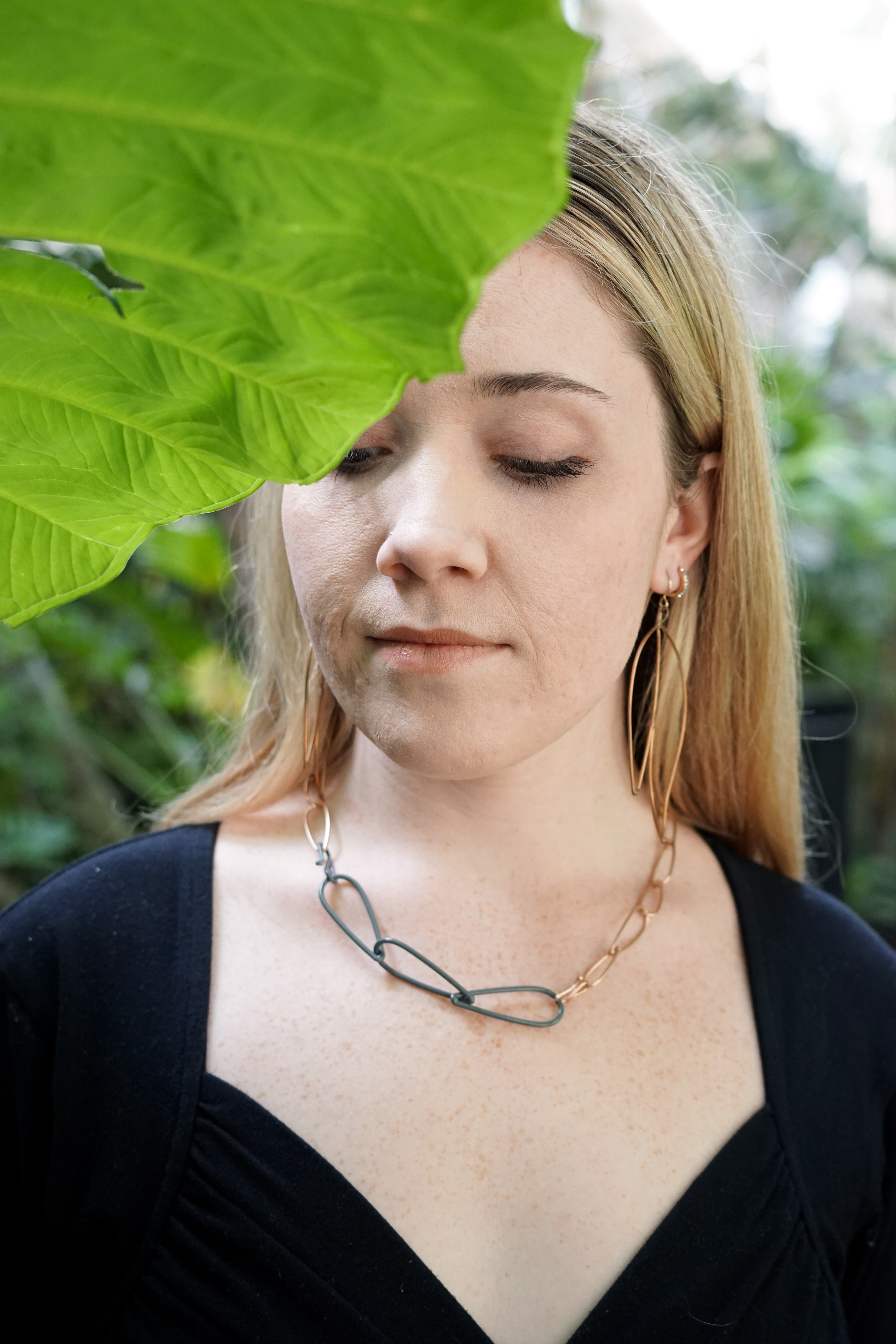 Trista wearing bronze and grey necklace and bronze statement earrings with large green leaf