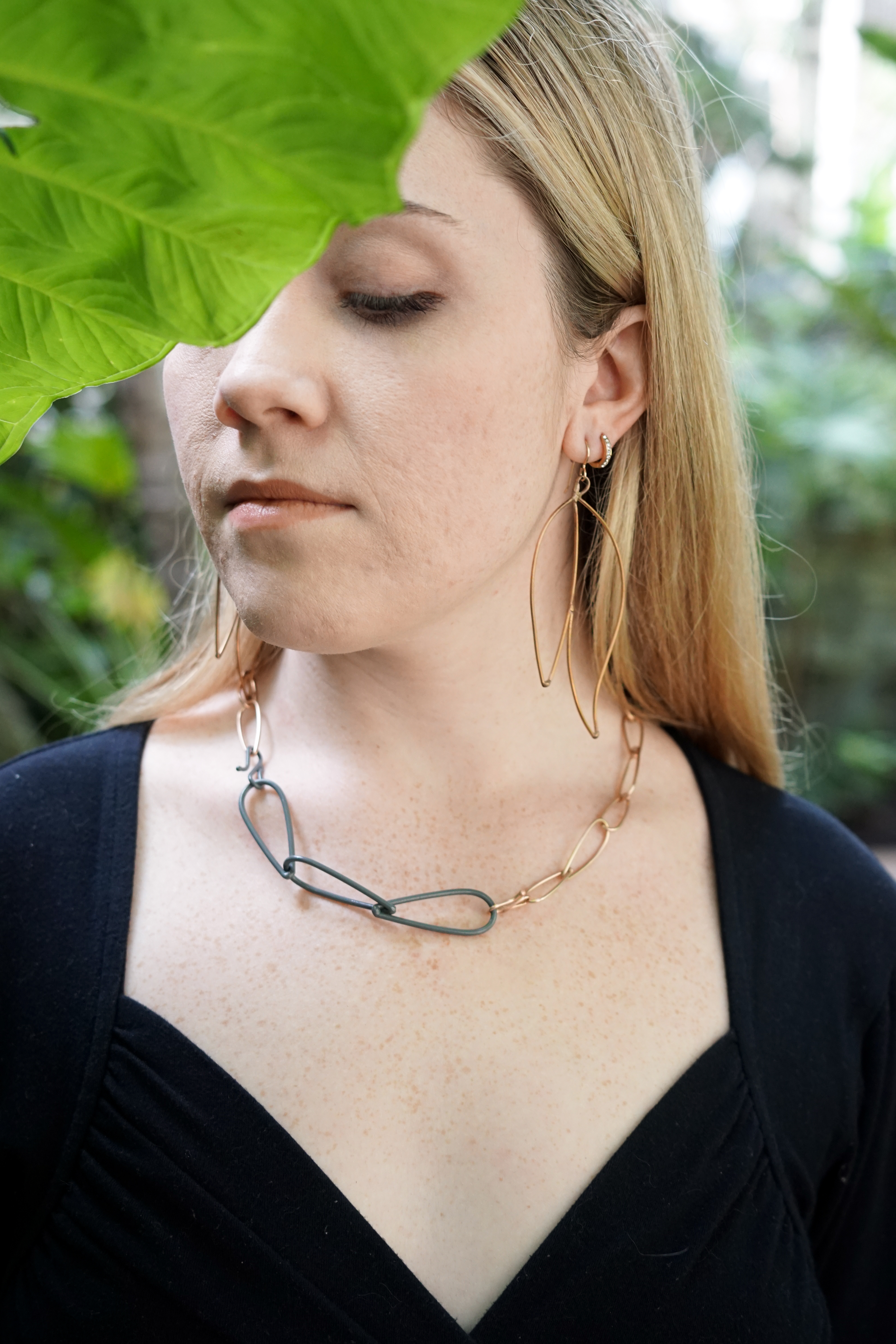 Trista wearing bronze and grey necklace and bronze statement earrings with large green leaf